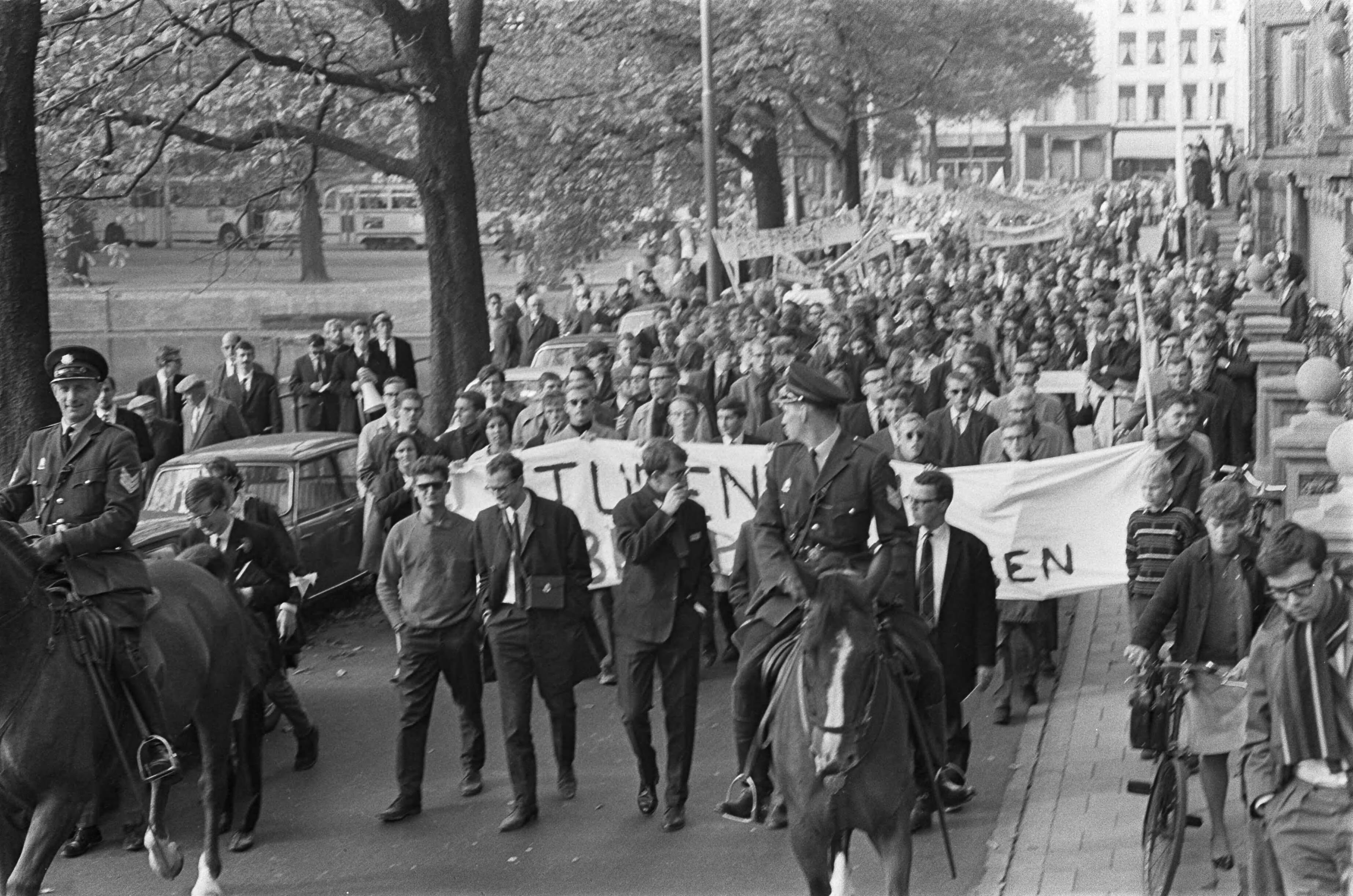 Studentendemonstratie inzake studietoelage, optocht van Amsterdam naar Den Haag — Betogende studenten lopen met spandoeken door Den Haag — Foto: Fotograaf Onbekend / Anefo. Licentie: Set B: Rechtenvrij / Publiek Domein. Bron: Nationaal Archief. http://hdl.handle.net/10648/aafe6a98-d0b4-102d-bcf8-003048976d84