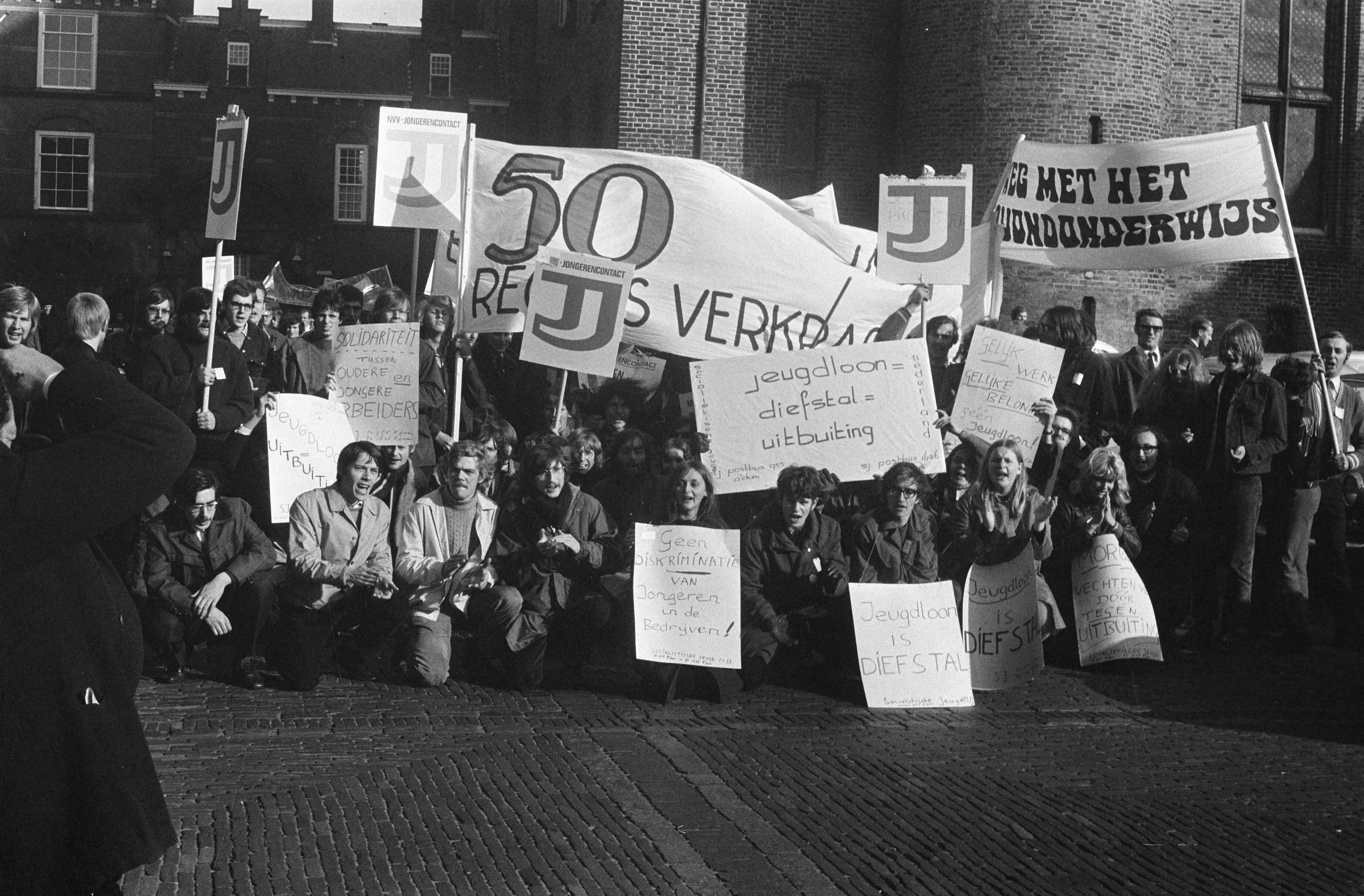 Fotocollectie Anefo — Demonstratie van Werkende Jongeren in Den Haag . Demonstranten met borden op Binnenhof — Foto: Verhoeff, Bert / Anefo. Licentie: Set B: Rechtenvrij / Publiek Domein. Bron: Nationaal Archief. http://hdl.handle.net/10648/ab7fa950-d0b4-102d-bcf8-003048976d84