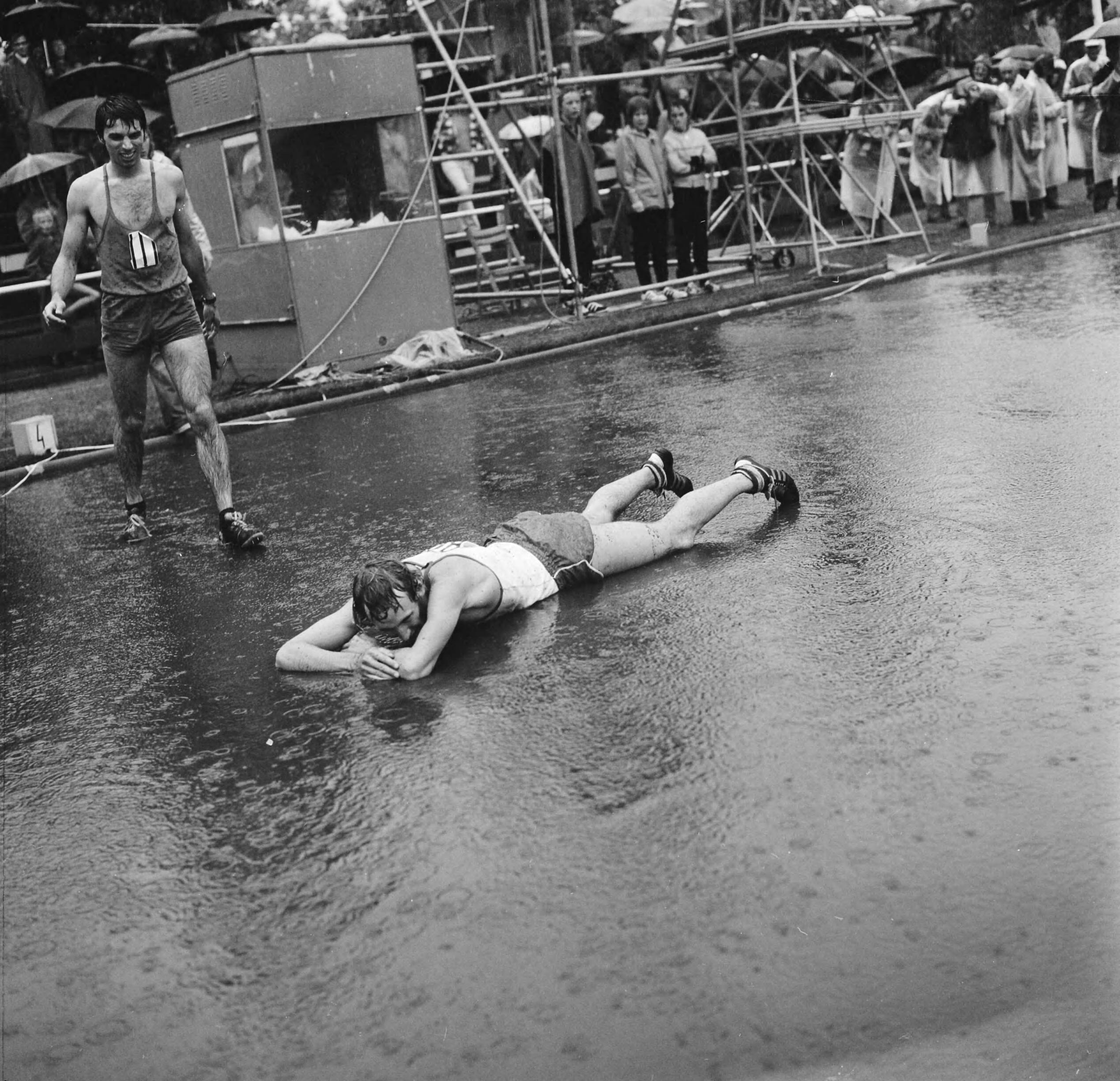 Fotocollectie Anefo — Nederlandse Atletiekkampioenschappen te Den Haag in de regen, Jan Willem Boogman ligt languit in water (na 800 meter hardlopen) — Foto: Mieremet, Rob / Anefo. Licentie: Set B: Rechtenvrij / Publiek Domein. Bron: Nationaal Archief. http://hdl.handle.net/10648/ac31ad26-d0b4-102d-bcf8-003048976d84