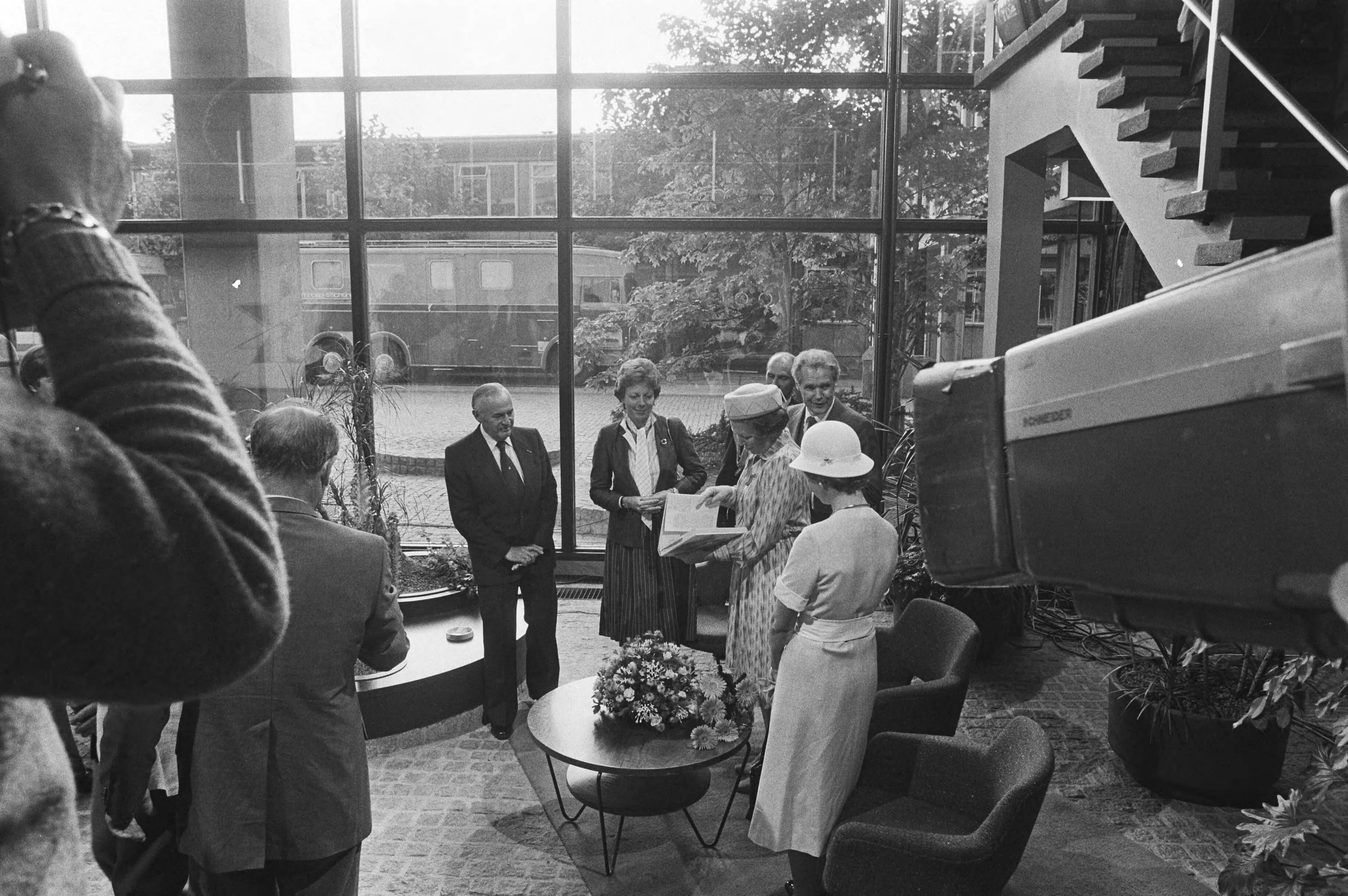 Bezoek van Koningin Beatrix aan de PTT in verband met het 100-jarig bestaan — Koningin Beatrix bekijkt met onder andere staatssecretaris Smit-Kroes het boek "Honderd jaar telefonie" — Foto: Dijk, Hans van / Anefo. Licentie: Set B: Rechtenvrij / Publiek Domein. Bron: Nationaal Archief. http://hdl.handle.net/10648/ad02a430-d0b4-102d-bcf8-003048976d84