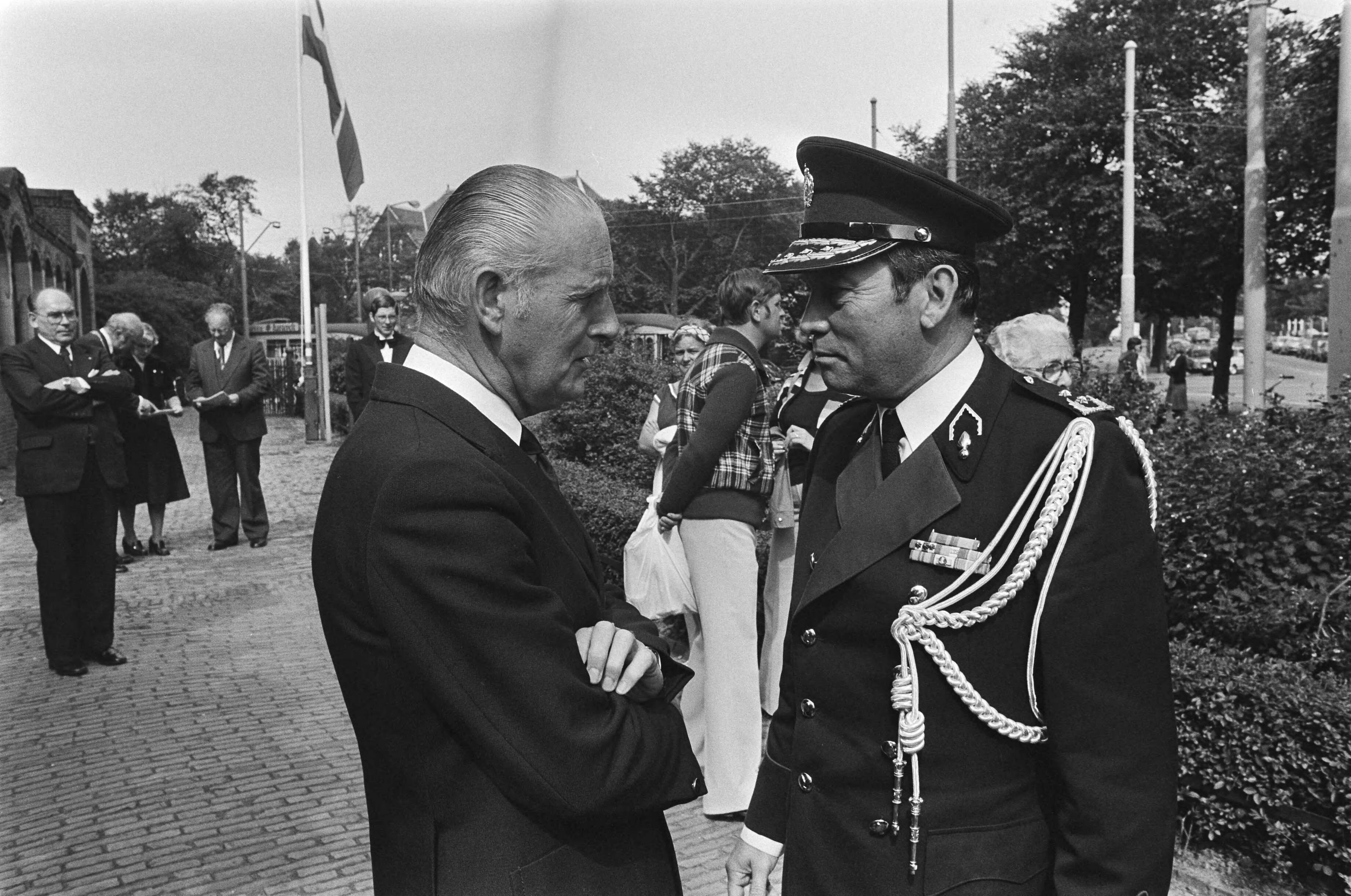 Fotocollectie Anefo — koningin Juliana onthult gevelsteen in Scheveningen van huis waar Prinses Wilhelmina even na de oorlog woonde; RVD-er Koeman met hoofd Marechaussee — Foto: Peters, Hans / Anefo. Licentie: Set B: Rechtenvrij / Publiek Domein. Bron: Nationaal Archief. http://hdl.handle.net/10648/aca1e97e-d0b4-102d-bcf8-003048976d84