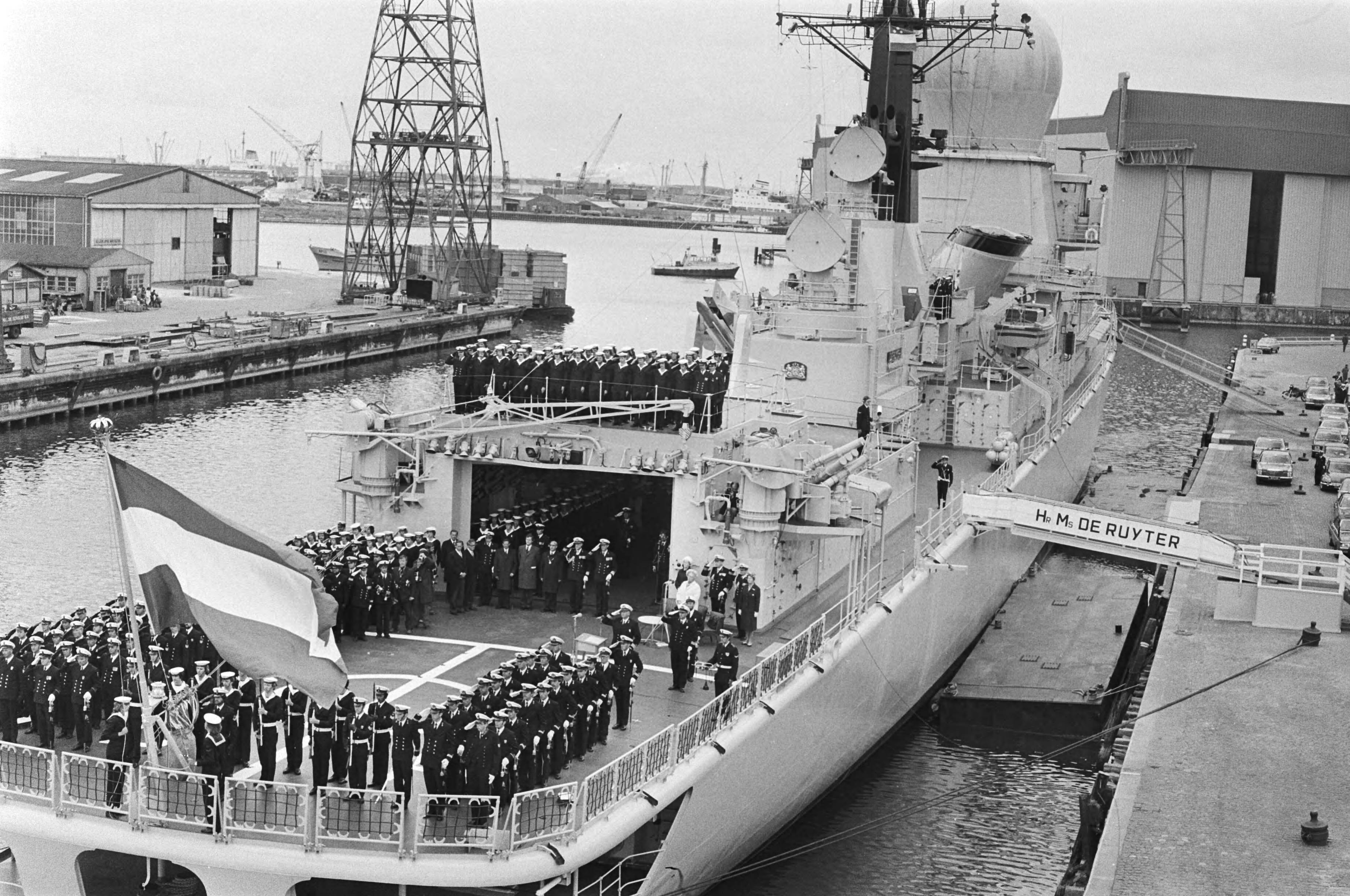 Fotocollectie Anefo — Wapenfregat De Ruyter door koningin Juliana in gebruik gesteld in Vlissingen, overzicht tijdens hijsen van vlag koningin Juliana — Foto: Verhoeff, Bert / Anefo. Licentie: Set B: Rechtenvrij / Publiek Domein. Bron: Nationaal Archief. http://hdl.handle.net/10648/ac856380-d0b4-102d-bcf8-003048976d84