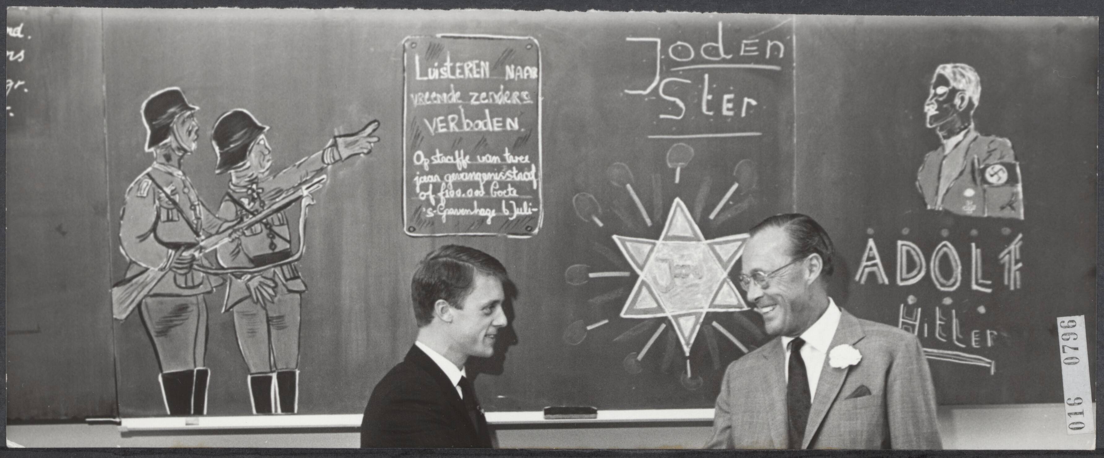 Fotocollectie Elsevier Binnenland — In Leeuwarden heeft prins Bernhard een christelijke lagere school geopend, die Prins Bernhardschool werd gedoopt. De school staat in een wijk waar de straatnamen herinneren aan het verzet. De prins tijdens de rondgang. De onderwijzers hebben op de schoolborden tekeningen gemaakt over de bezettingsperiode — Foto: Koch, Eric / Anefo. Licentie: Set B: Rechtenvrij / Publiek Domein. Bron: Nationaal Archief. http://hdl.handle.net/10648/adba766e-d0b4-102d-bcf8-003048976d84