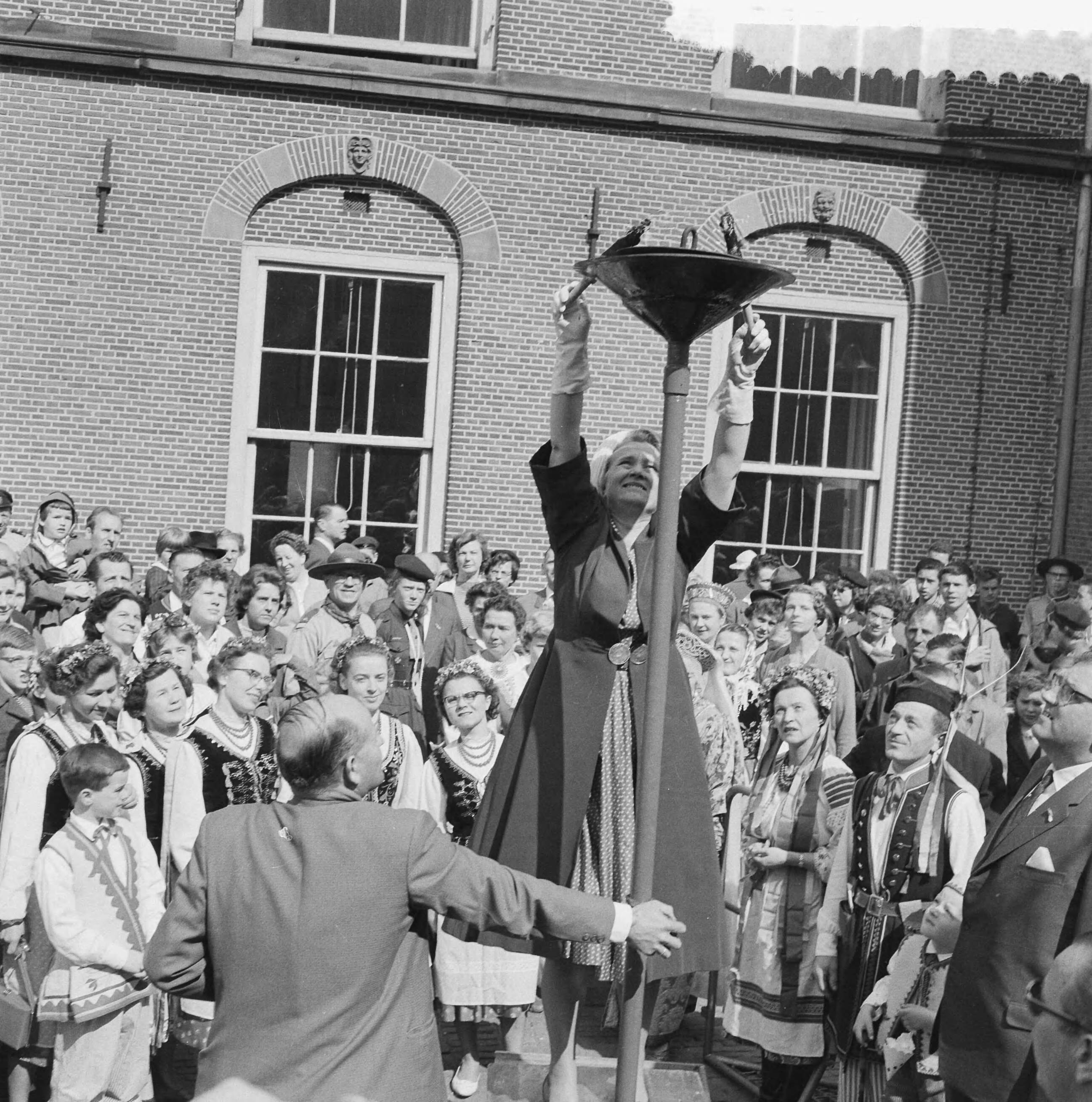 Fotocollectie Anefo — Ontsteken van het bevrijdingsvuur door minister Klompé op het Binnenhof te Den Haag — Foto: Behrens, Herbert F. / Anefo. Licentie: Set B: Rechtenvrij / Publiek Domein. Bron: Nationaal Archief. http://hdl.handle.net/10648/a9adf938-d0b4-102d-bcf8-003048976d84