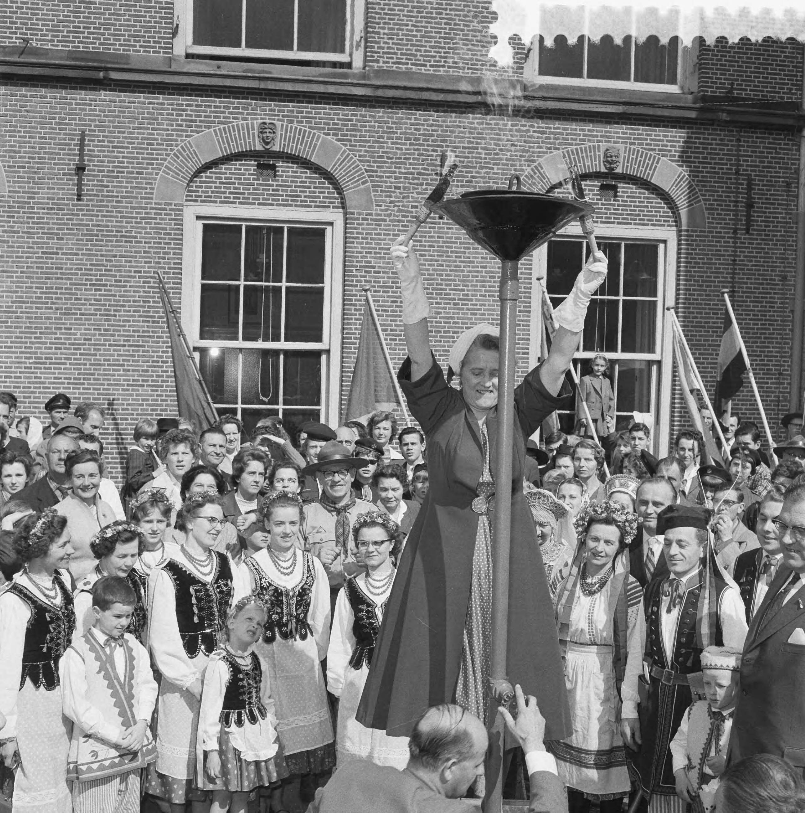 Fotocollectie Anefo — Ontsteken van het bevrijdingsvuur door minister Klompé op het Binnenhof te Den Haag — Foto: Behrens, Herbert F. / Anefo. Licentie: Set B: Rechtenvrij / Publiek Domein. Bron: Nationaal Archief. http://hdl.handle.net/10648/a9adf866-d0b4-102d-bcf8-003048976d84