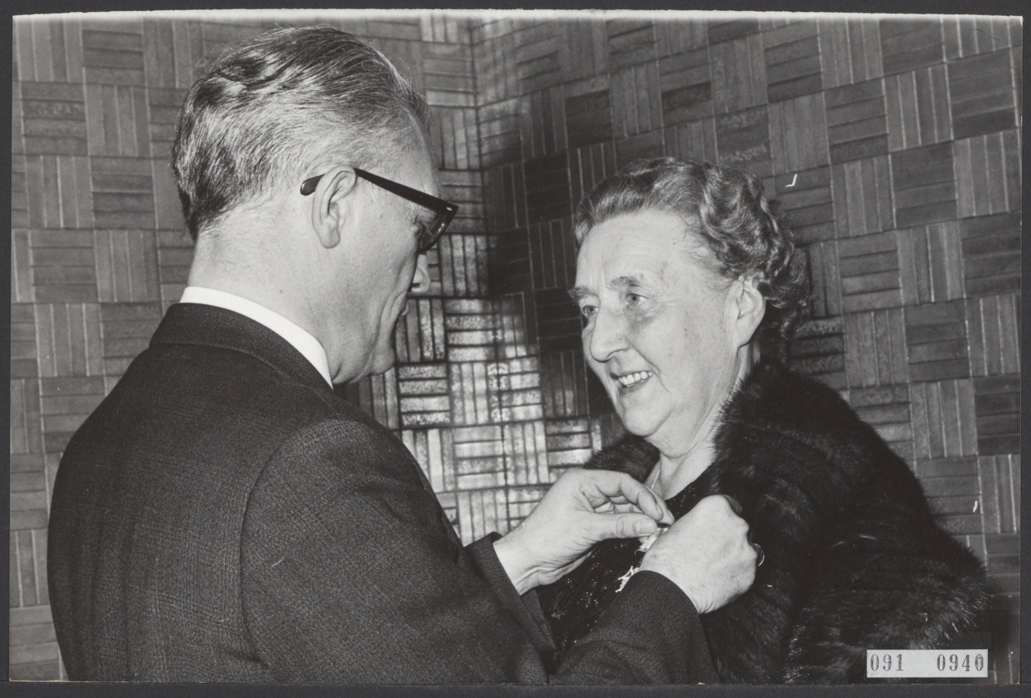 Fotocollectie Elsevier Binnenland — De burgemeester van Hilversum, J.J.G. Boot heeft afscheid genomen. Zowel hij als zijn echtgenote werden onderscheiden door de koningin. Mevr. W.A. Boot-Colijn krijgt de versierselen behorende bij Ridder in de Orde van Oranje Nassau uit handen van minister Roolvink (oud raadslid Hilversum) — Foto: Kroon, Ron / Anefo. Licentie: Set B: Rechtenvrij / Publiek Domein. Bron: Nationaal Archief. http://hdl.handle.net/10648/ae21792c-d0b4-102d-bcf8-003048976d84