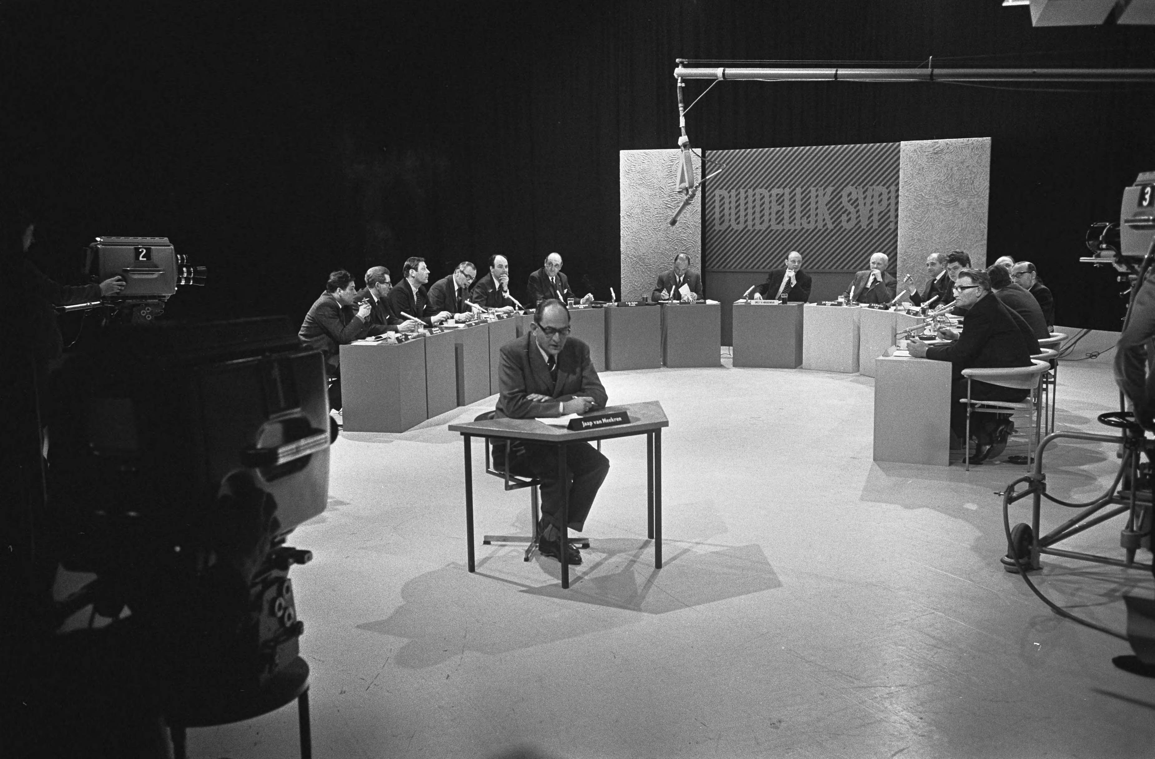 Fotocollectie Anefo — AVRO-TV, "Duidelijk svp" , zestien Nederlandse politici debatteren onder leiding van drs. F. A. Hoogendijk (midden) — Foto: Koch, Eric / Anefo. Licentie: Set B: Rechtenvrij / Publiek Domein. Bron: Nationaal Archief. http://hdl.handle.net/10648/ab34de98-d0b4-102d-bcf8-003048976d84