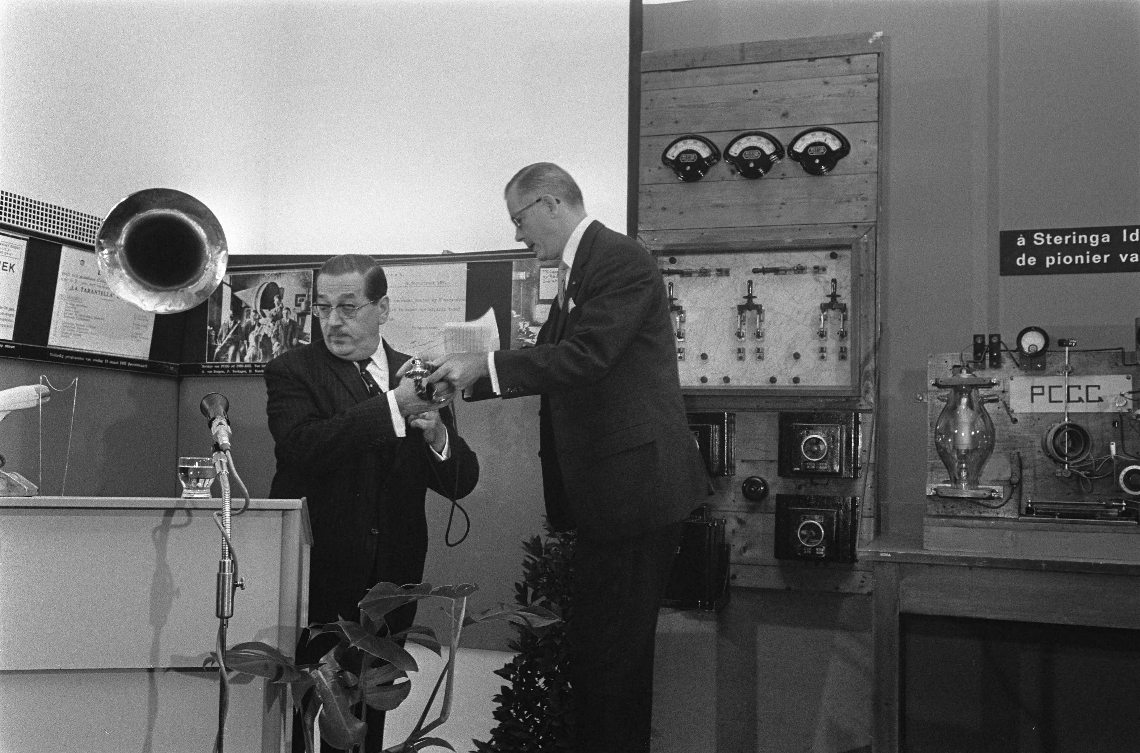 Fotocollectie Anefo — Herdenking van radiopionier Hans Henricus Schotanus á Steringa Idzerda(verzorgde 50 jaar geleden eerste radiouitzending) in Postmuseum Den Haag . Van der Poel (staatssecretaris) — Foto: Koch, Eric / Anefo. Licentie: Set B: Rechtenvrij / Publiek Domein. Bron: Nationaal Archief. http://hdl.handle.net/10648/ab806836-d0b4-102d-bcf8-003048976d84