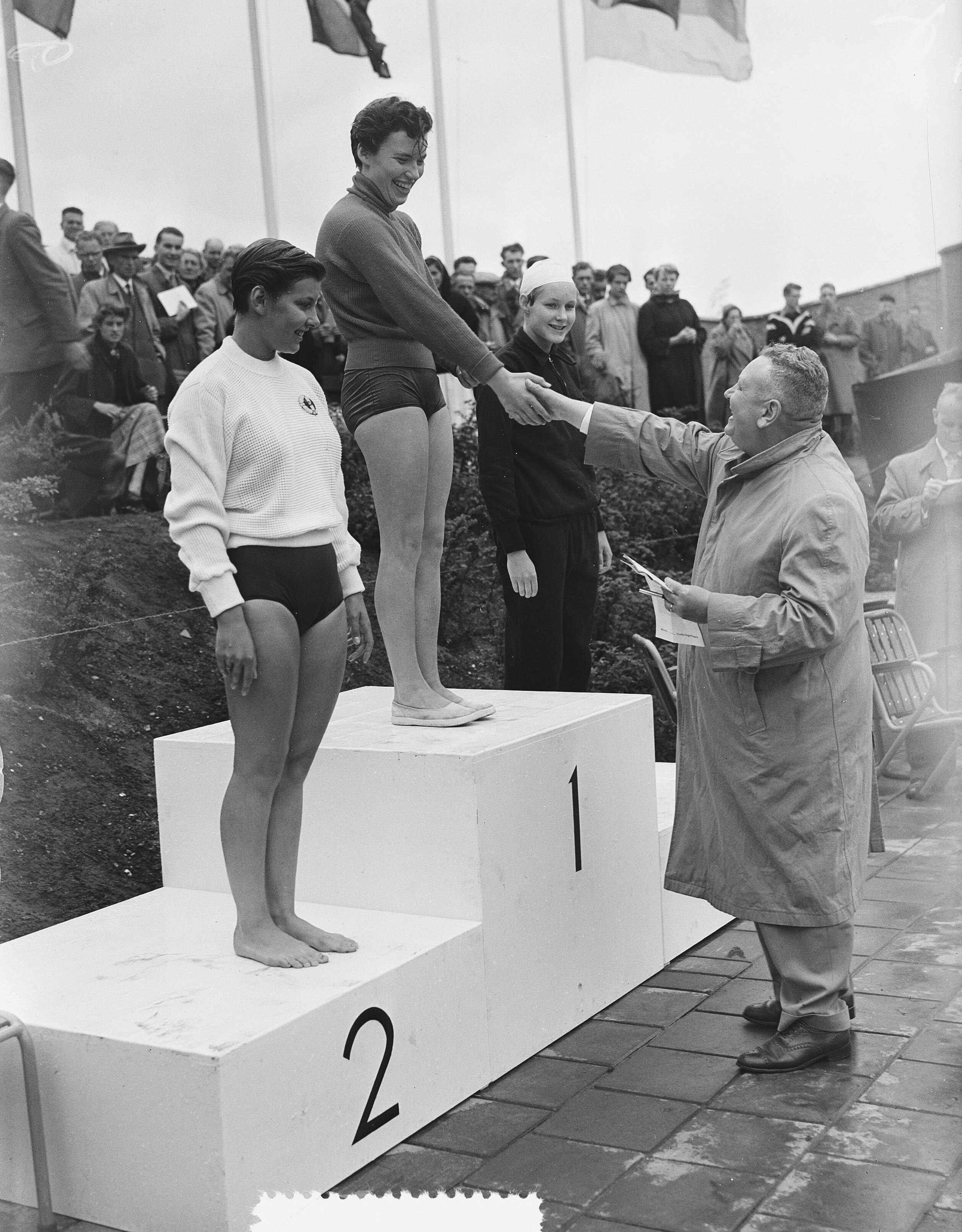 Fotocollectie Anefo — Nederlandse kampioenschappen zwemmen te Groningen, Huldiging 100 m vrije slag dames. Winnares Hetty Balkenende wordt gefeliciteerd. Links Jopie van Alphen (2e) en rechts Corrie Gastelaars (3e)] — Foto: Bilsen, Joop van / Anefo. Licentie: Set B: Rechtenvrij / Publiek Domein. Bron: Nationaal Archief. http://hdl.handle.net/10648/a9393c88-d0b4-102d-bcf8-003048976d84