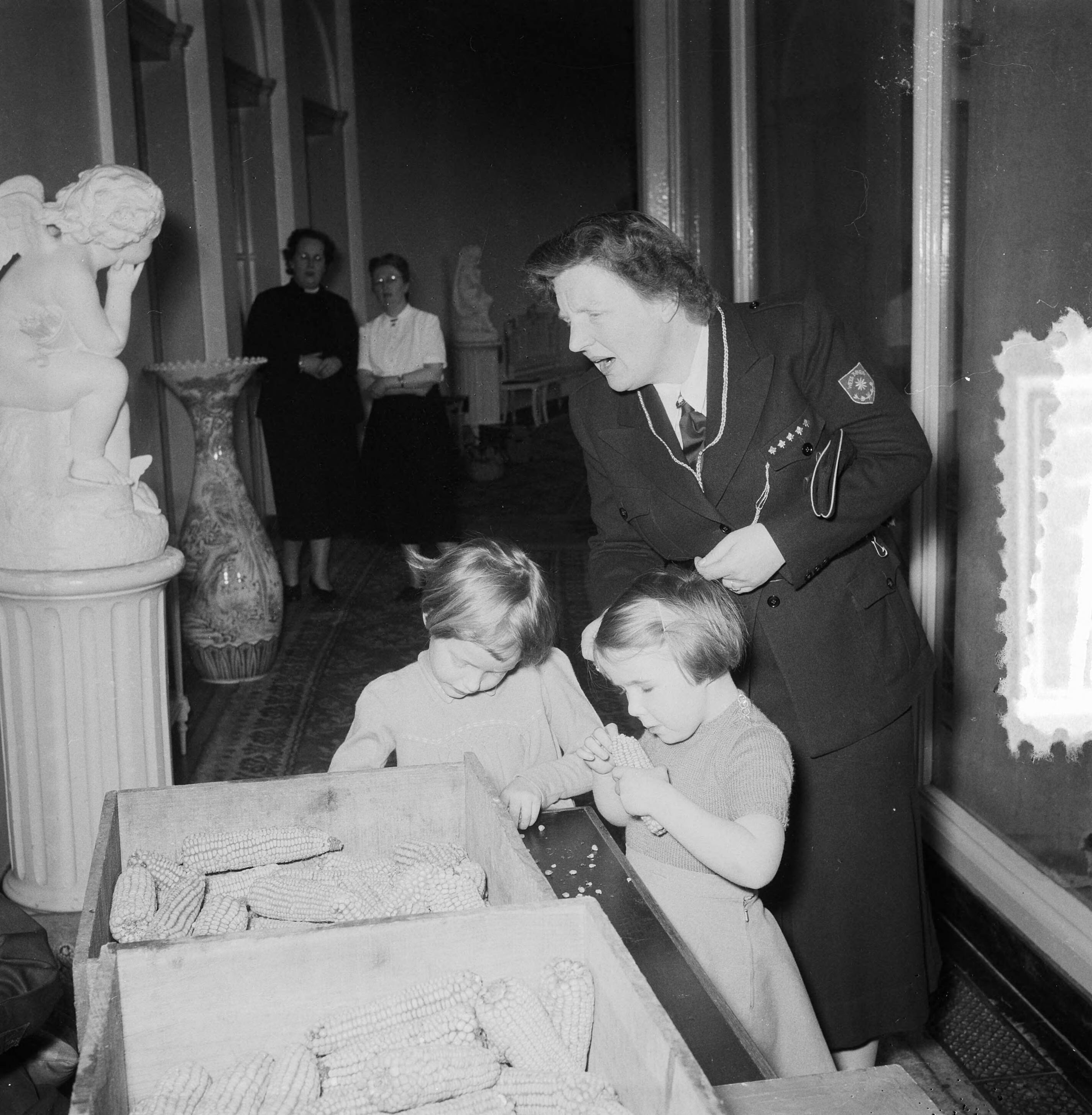 Soestdijk. Padvinders actie "Heitje voor Karweitje" — Soestdijk. Padvinders actie "Heitje voor Karweitje". Koningin Juliana en prinses Marijke bekijken maiskolven — Foto: Noske, J.D. / Anefo. Licentie: Set B: Rechtenvrij / Publiek Domein. Bron: Nationaal Archief. http://hdl.handle.net/10648/a909b77e-d0b4-102d-bcf8-003048976d84