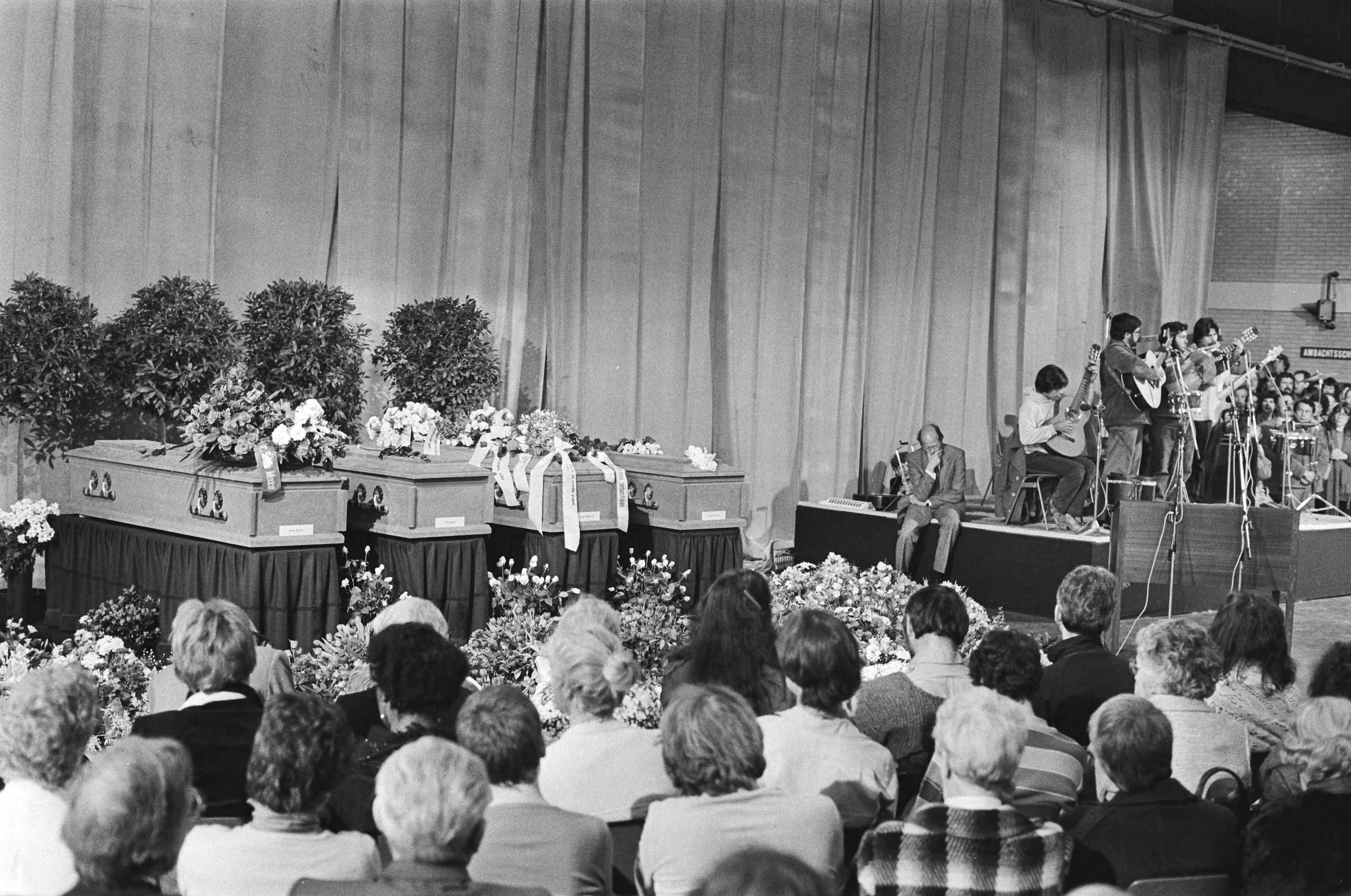 Fotocollectie Anefo — Herdenkingsbijeenkomst voor het in El Salvador omgekomen IKON-team in de decorhal van de NOS in Hilversum — Foto: Bogaerts, Rob / Anefo. Licentie: Set B: Rechtenvrij / Publiek Domein. Bron: Nationaal Archief. http://hdl.handle.net/10648/ad13d016-d0b4-102d-bcf8-003048976d84