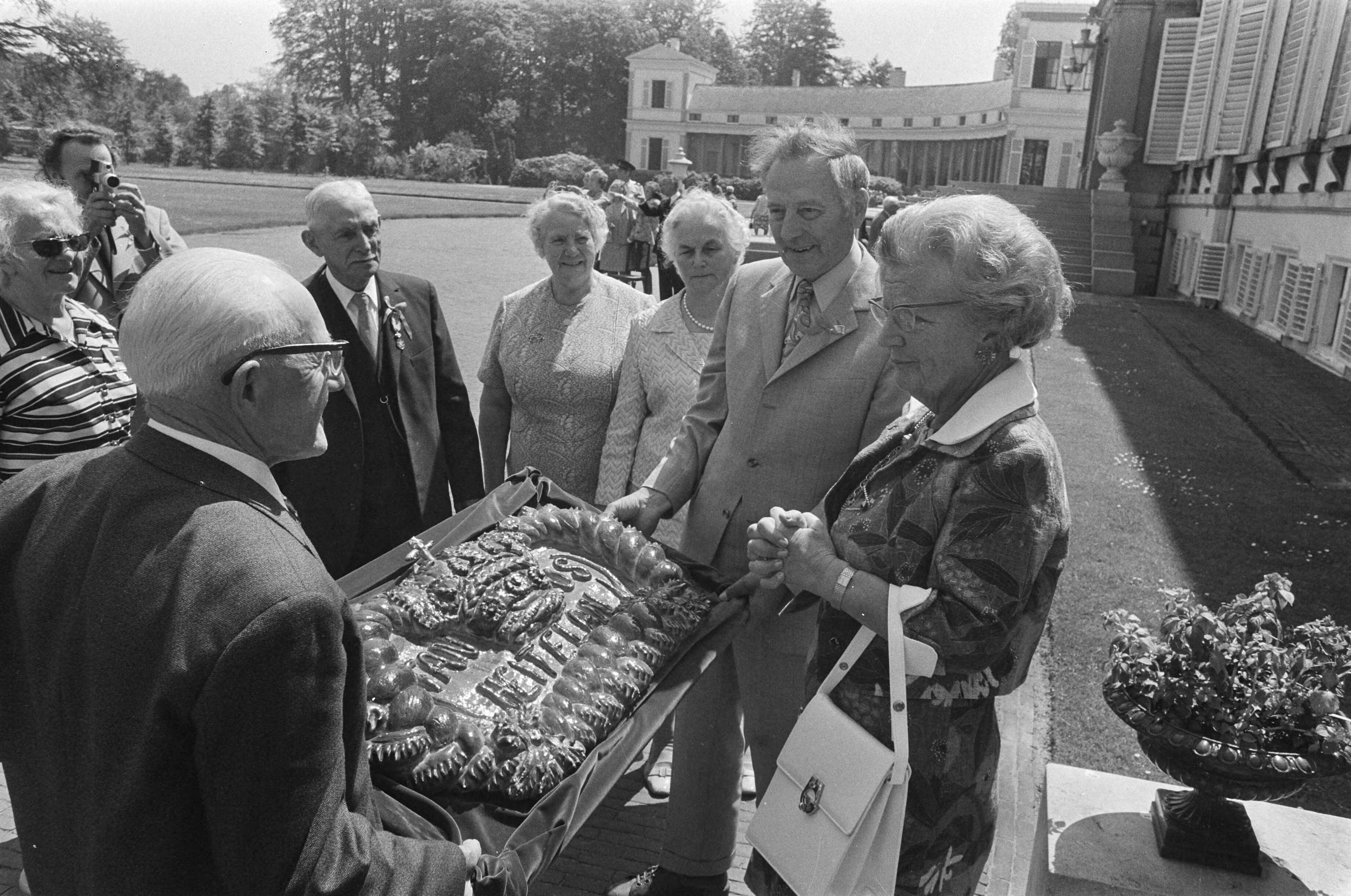 Bejaardendefilé op Paleis Soestdijk — Koningin Juliana krijgt een grote taart uit Delfzijl — Foto: Fotograaf Onbekend / Anefo. Licentie: Set B: Rechtenvrij / Publiek Domein. Bron: Nationaal Archief. http://hdl.handle.net/10648/ac4ca798-d0b4-102d-bcf8-003048976d84