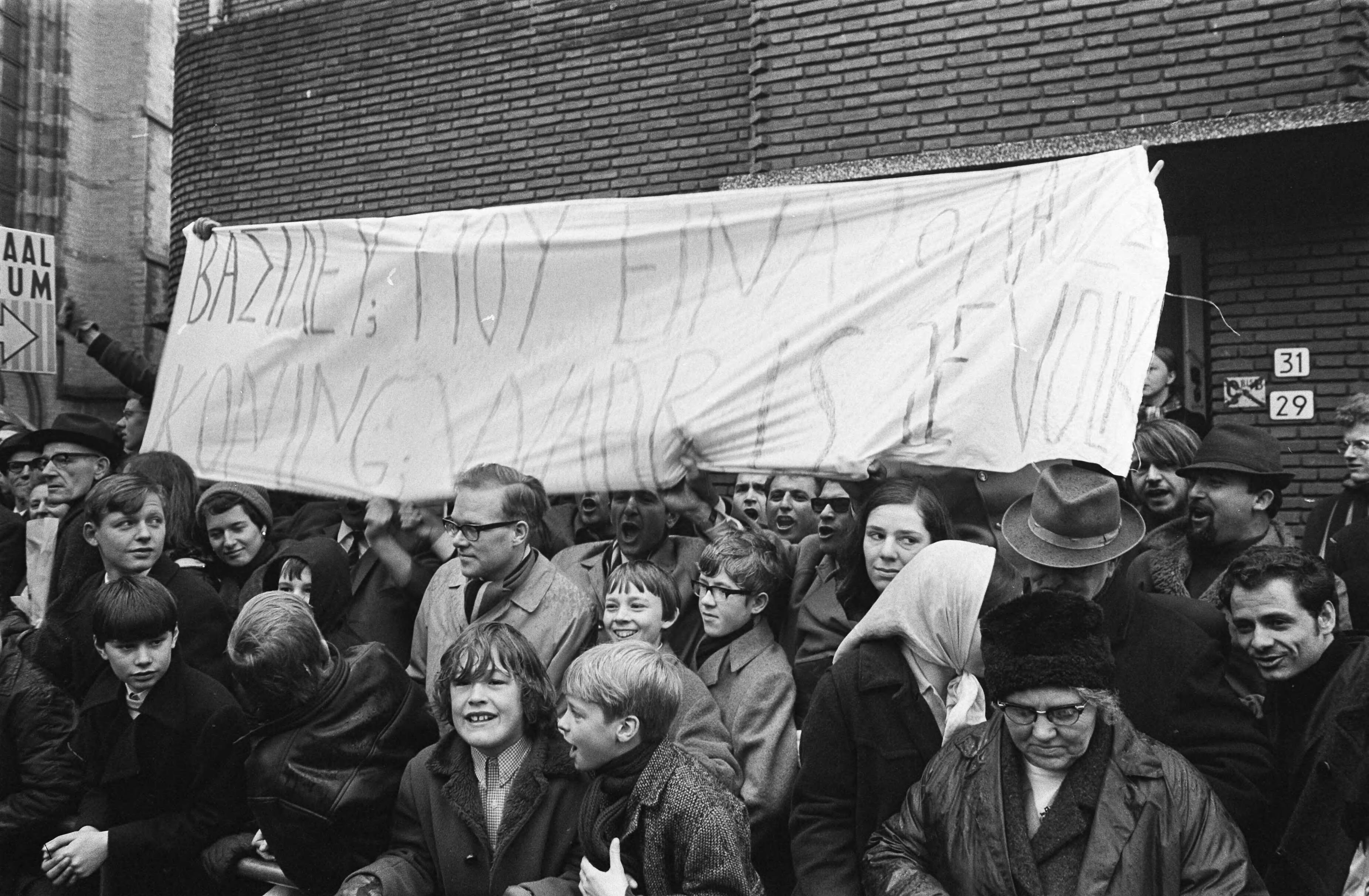 Fotocollectie Anefo — Demonstranten met spandoek voor Domkerk tegen aanwezigheid van koning Constantijn van Griekenland te Utrecht — Foto: Koch, Eric / Anefo. Licentie: Set B: Rechtenvrij / Publiek Domein. Bron: Nationaal Archief. http://hdl.handle.net/10648/ab8e3998-d0b4-102d-bcf8-003048976d84