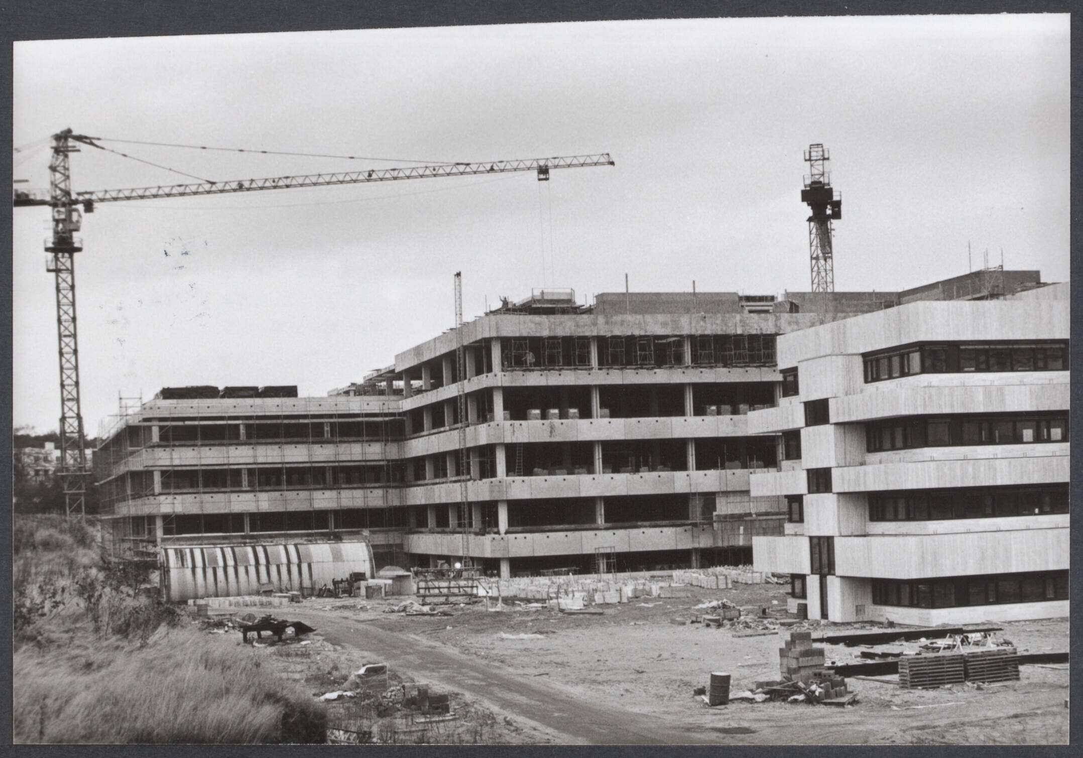 NOS. en NTS - Nederland — Het hoogste punt is bereikt van de nieuwbouw bij de Nederlandse Omroep Stichting te Hilversum. Op 16 juni 1978 werd de eerste steen gelegd van deze nieuwe gebouwen waaarin het film-, schakel- en presentatiecentrum ondergebracht zullen worden — Foto: Duinen, G.W. van / Anefo. Licentie: Set B: Rechtenvrij / Publiek Domein. Bron: Nationaal Archief. http://hdl.handle.net/10648/72d980e0-5761-4ea2-392c-c68e586ae5e7