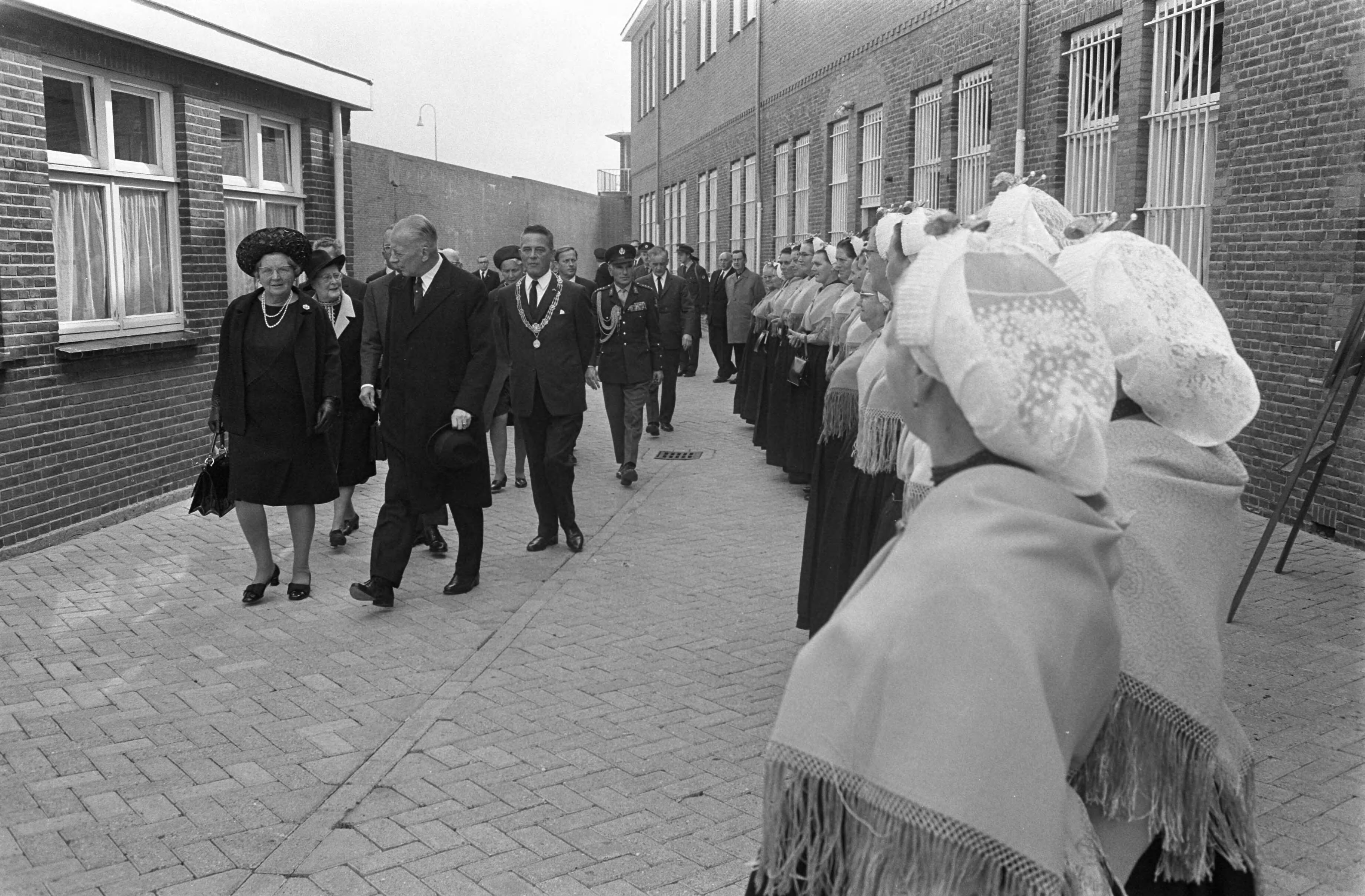Fotocollectie Anefo — koningin Juliana en Prins Bernhard bij 25e Dodenherdenking in Scheveningse gevangenis bij Cel 601 ; Scheveningse vissersvrouwen bij aankomst / — Foto: Koch, Eric / Anefo. Licentie: Set B: Rechtenvrij / Publiek Domein. Bron: Nationaal Archief. http://hdl.handle.net/10648/aba30ed6-d0b4-102d-bcf8-003048976d84
