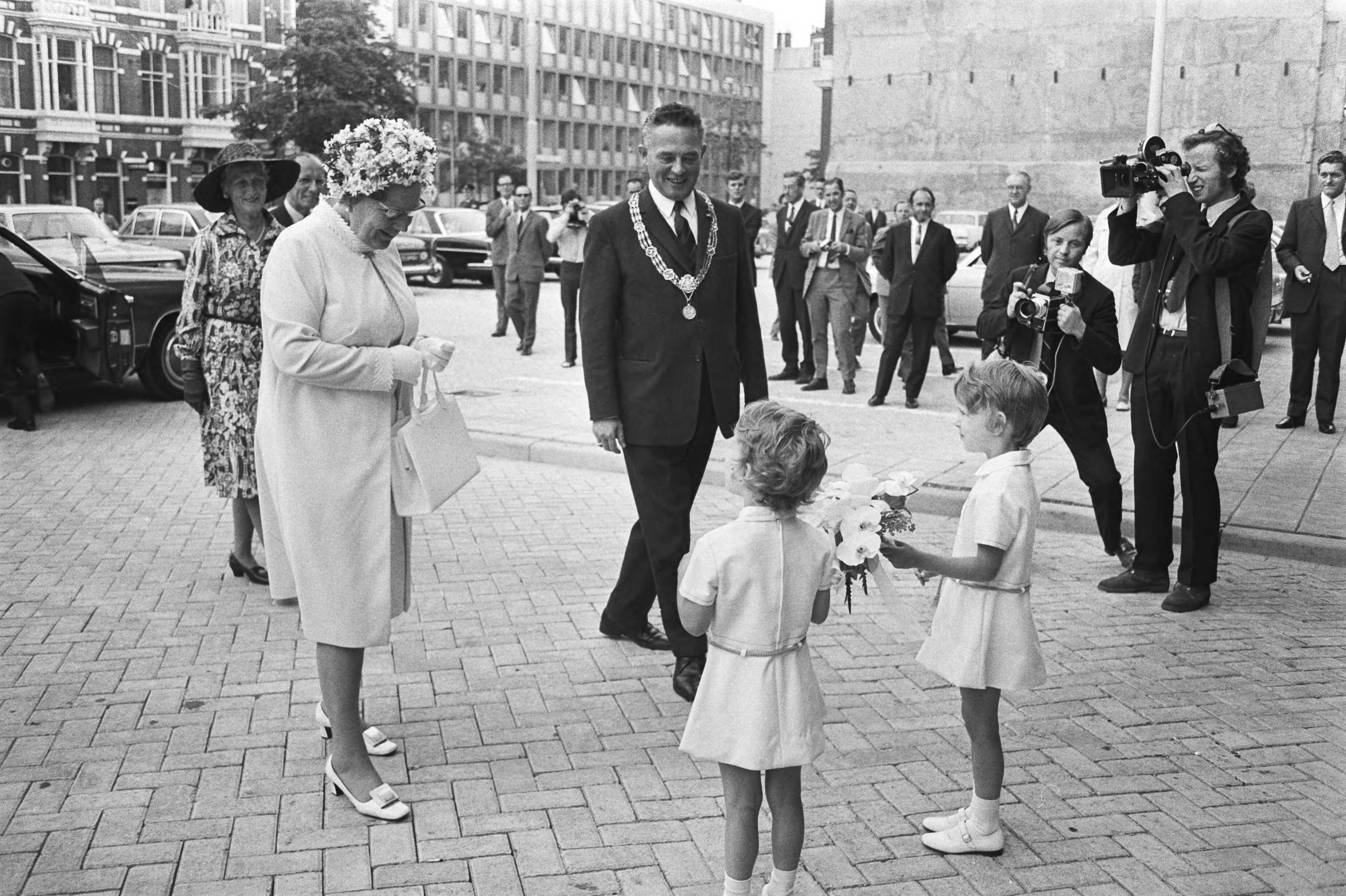 Koningin Juliana opent nieuwe SER gebouw Den Haag — Koningin Juliana krijgt bij haar aankomst bij het SER-gebouw bloemen aangeboden; rechts, met ambtsketen, burgemeester Marijnen van Den Haag — Foto: Fotograaf Onbekend / Anefo. Licentie: Set B: Rechtenvrij / Publiek Domein. Bron: Nationaal Archief. http://hdl.handle.net/10648/abc50676-d0b4-102d-bcf8-003048976d84