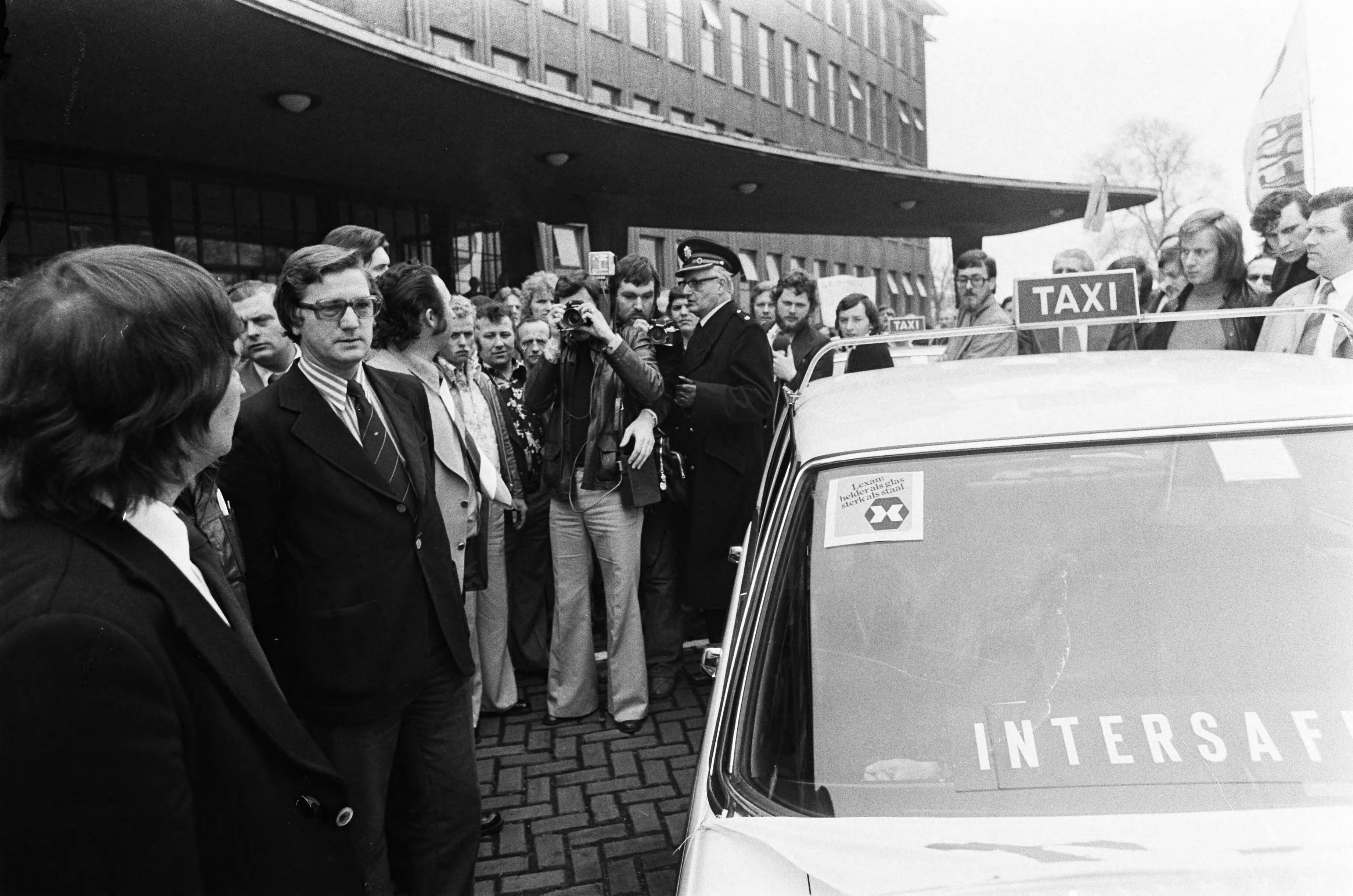 Demonstratie van taxichauffeurs in Den Haag en aanbieding van handtekeningen aan minister Tjerk Westerterp — Minister Tjerk Westerterp bekijkt een 'veilige' taxi — Foto: Mieremet, Rob / Anefo. Licentie: Set B: Rechtenvrij / Publiek Domein. Bron: Nationaal Archief. http://hdl.handle.net/10648/ac674b84-d0b4-102d-bcf8-003048976d84