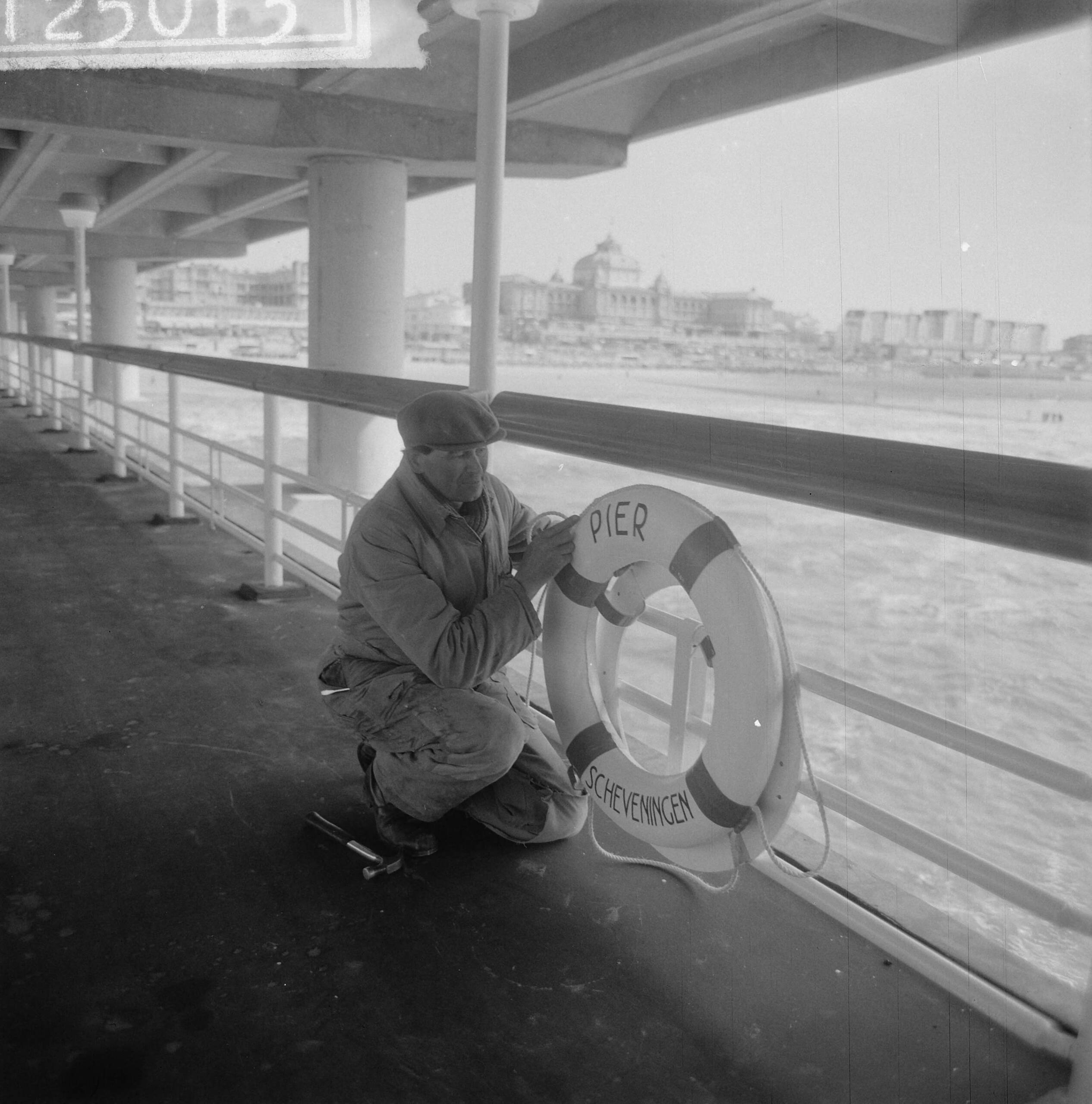Nieuwe Pier in Scheveningen — Nieuwe Pier in Scheveningen. Arbeider verzorgt de reddingsboeien — Foto: Nijs, Jac. de / Anefo. Licentie: Set B: Rechtenvrij / Publiek Domein. Bron: Nationaal Archief. http://hdl.handle.net/10648/a9d5ada2-d0b4-102d-bcf8-003048976d84