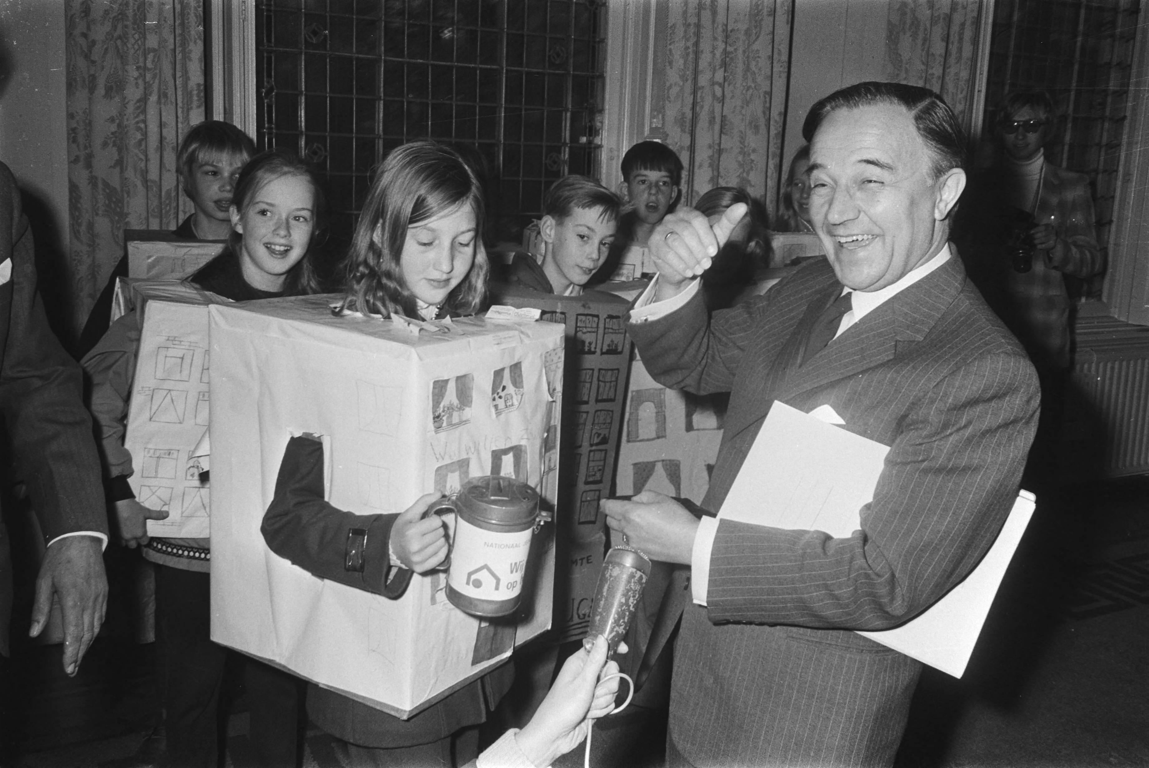 Fotocollectie Anefo — 500 lagere schoolkinderen vragen Premier De Jong om speel- en leefruimte, Den Haag; meisje met collectebus bij De Jong — Foto: Koch, Eric / Anefo. Licentie: Set B: Rechtenvrij / Publiek Domein. Bron: Nationaal Archief. http://hdl.handle.net/10648/abaa15be-d0b4-102d-bcf8-003048976d84