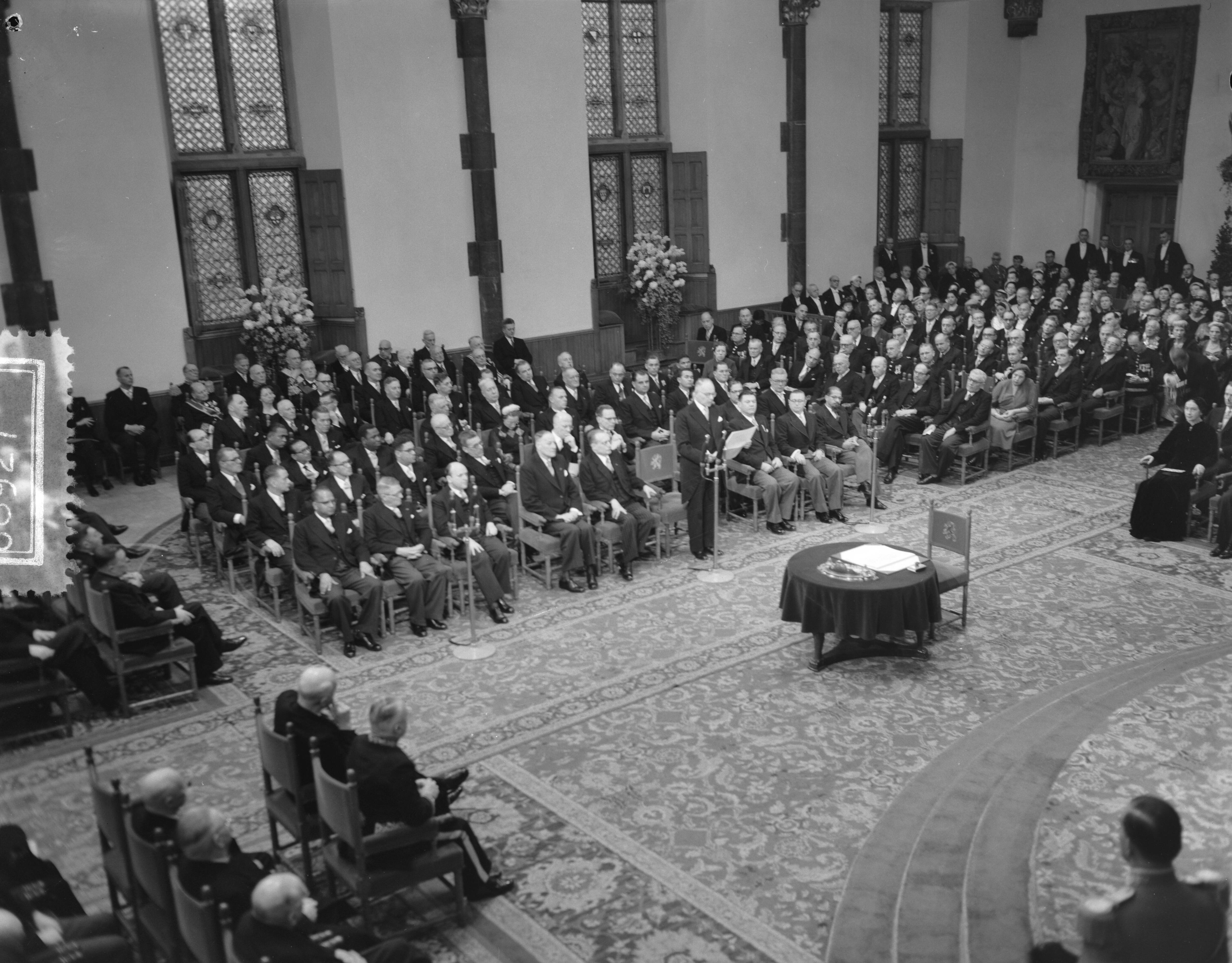 Koningin Juliana ondertekent in een plechtige bijeenkomst in de Ridderzaal in Den Haag de Acte van Bevestiging van het Statuut voor het Koninkrijk — Ondertekening van de Acte van Bevestiging van het Statuut van het Koninkrijk in de Ridderzaal te Den Haag. Een van de ministers houdt een toespraak — Foto: Noske, J.D. / Anefo. Licentie: Set B: Rechtenvrij / Publiek Domein. Bron: Nationaal Archief. http://hdl.handle.net/10648/a92e21c2-d0b4-102d-bcf8-003048976d84