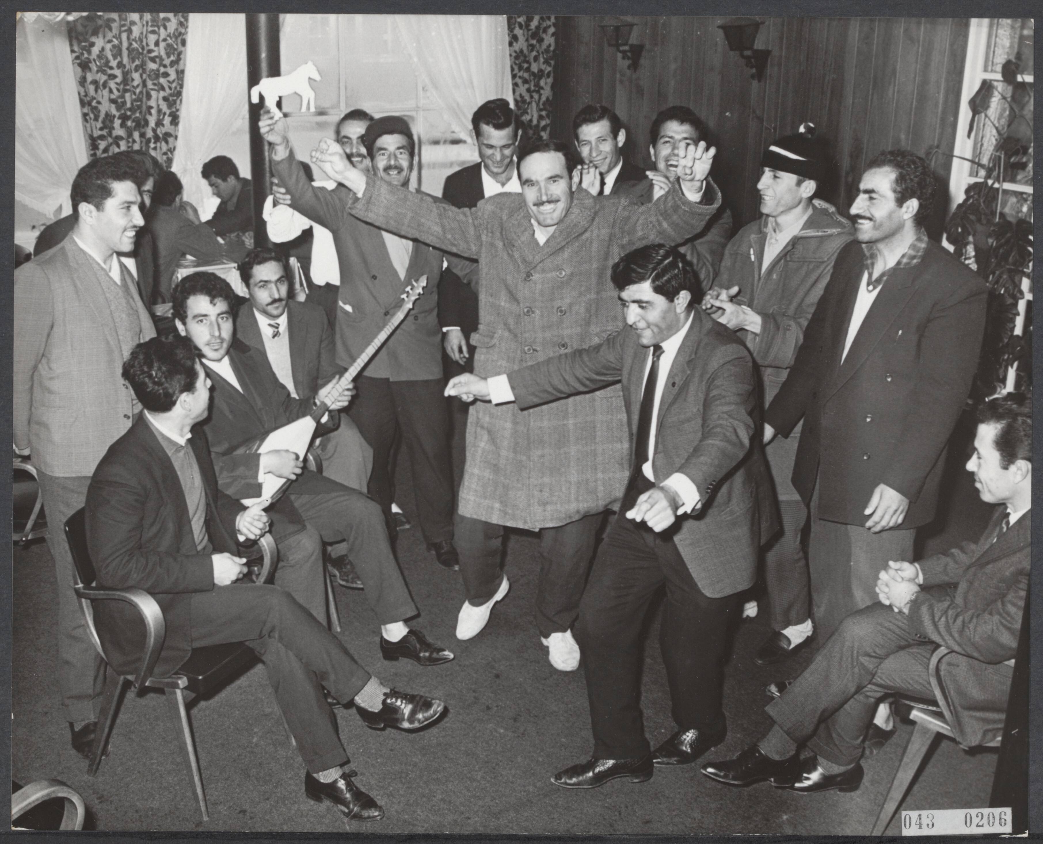 Fotocollectie Elsevier Binnenland — Een honderdtal stakende Turken, werkzaam bij het Zaanse bouwbedrijf N.V. Indeco Coignet logeren in een hotel in Zandvoort. Zij eisen een flinke loonsverhoging, maar dansen er nu vrolijk op los bij gitaarmuziek — Foto: Koch, Eric / Anefo. Licentie: Set B: Rechtenvrij / Publiek Domein. Bron: Nationaal Archief. http://hdl.handle.net/10648/adf88cc4-d0b4-102d-bcf8-003048976d84