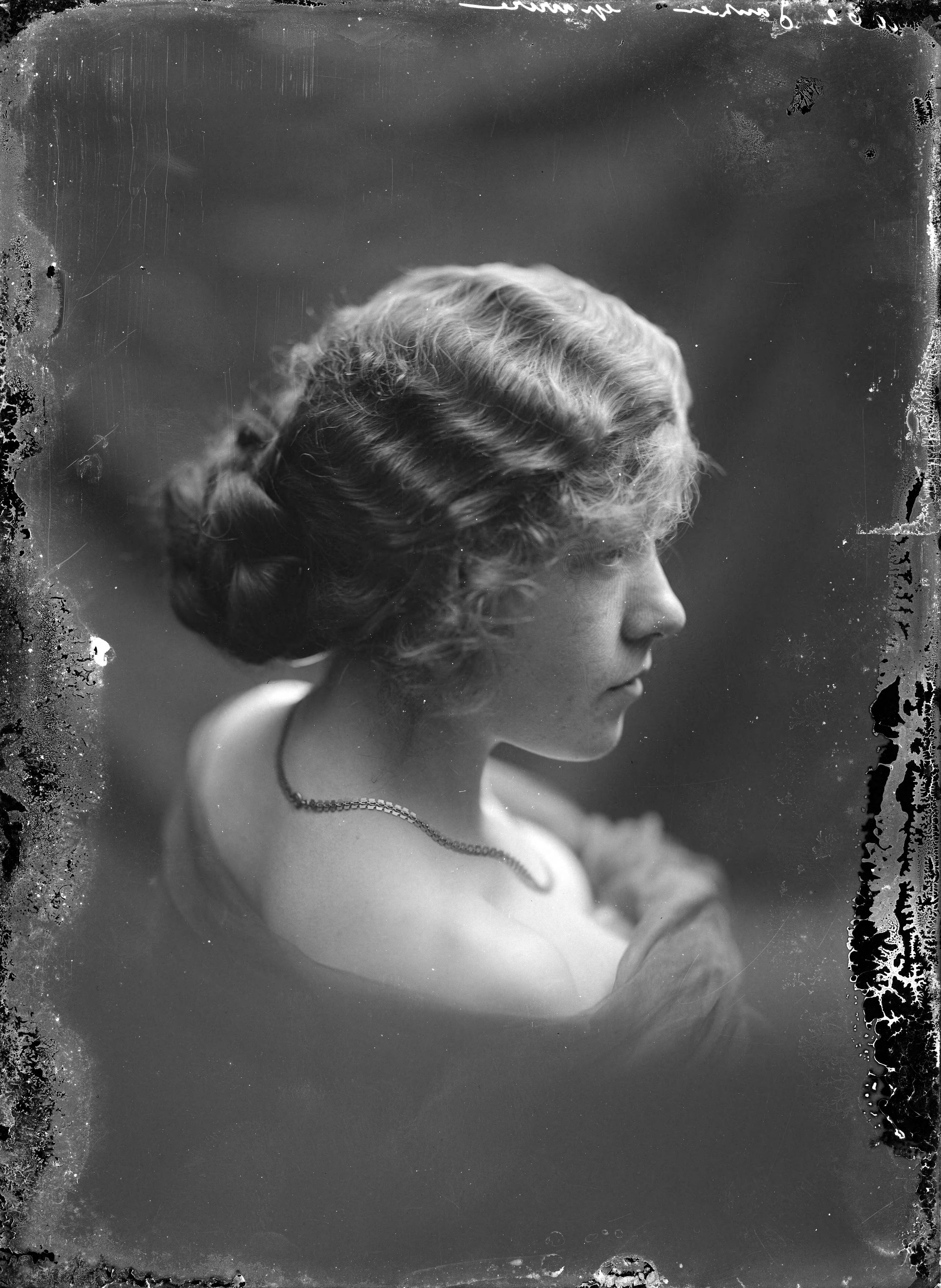 Portretten — Studio-opnames. Portret en profiel, van een jong meisje met golvend lang haar in een knot en met blote schouders. Rechtsboven op glasnegatief: 1062 Janzen gravure. Haarlem, Nederland 1918-1930 — Foto: Berg, Th.C.J. van den / Spaarnestad Photo (05887). Licentie: Set B: Rechtenvrij / Publiek Domein. Bron: Nationaal Archief. http://hdl.handle.net/10648/35429da7-c54a-a382-e063-6df0900a6686