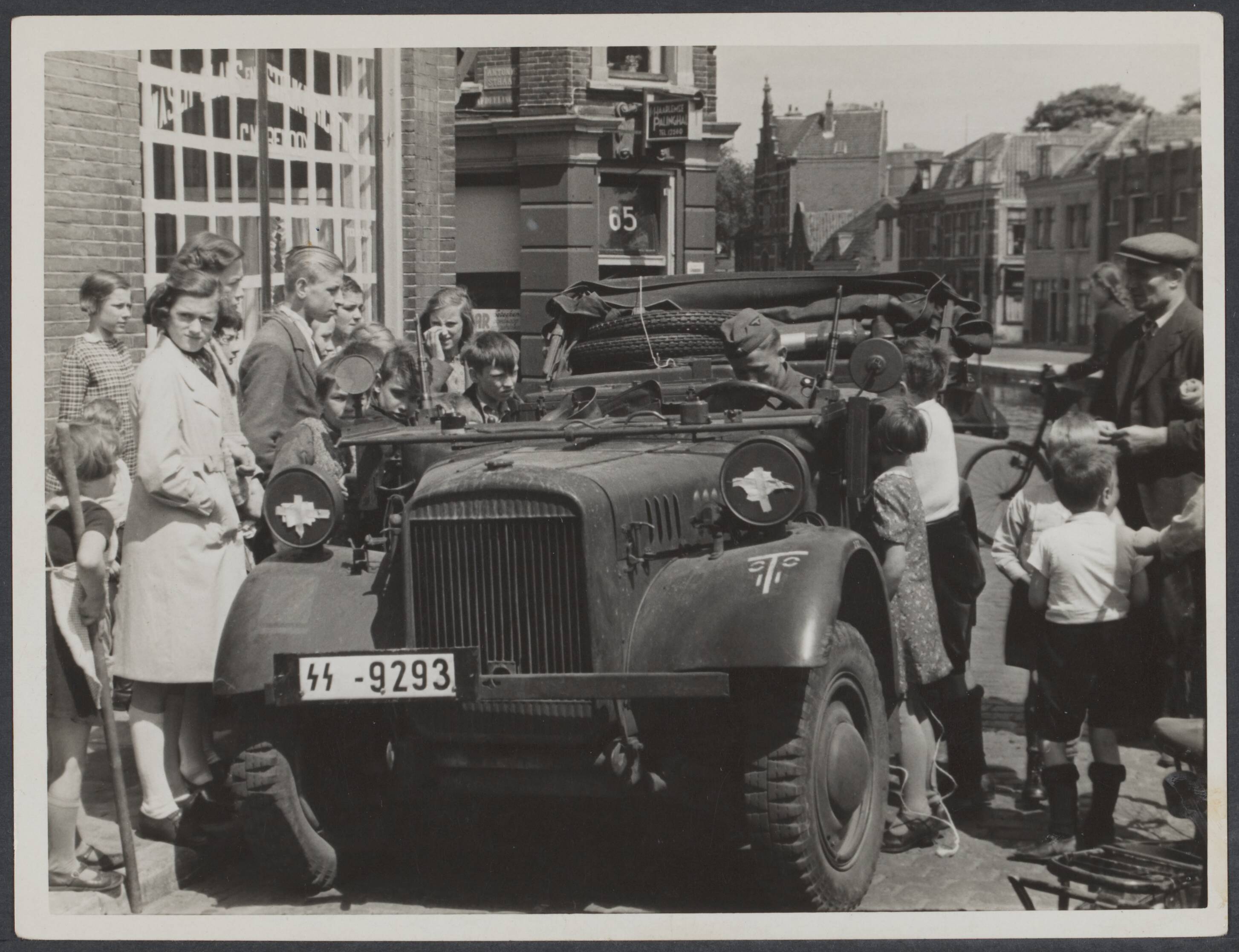 Nederlands Front - Meidagen '40. — Duitse troepen. Belangstelling van de jeugd voor een Duitse militaire auto in Haarlem — Foto: Valks, H.J.M. / Spaarnestad. Licentie: Set B: Rechtenvrij / Publiek Domein. Bron: Nationaal Archief. http://hdl.handle.net/10648/6a8c53a2-5904-2c8e-2aae-f0f1263881c6