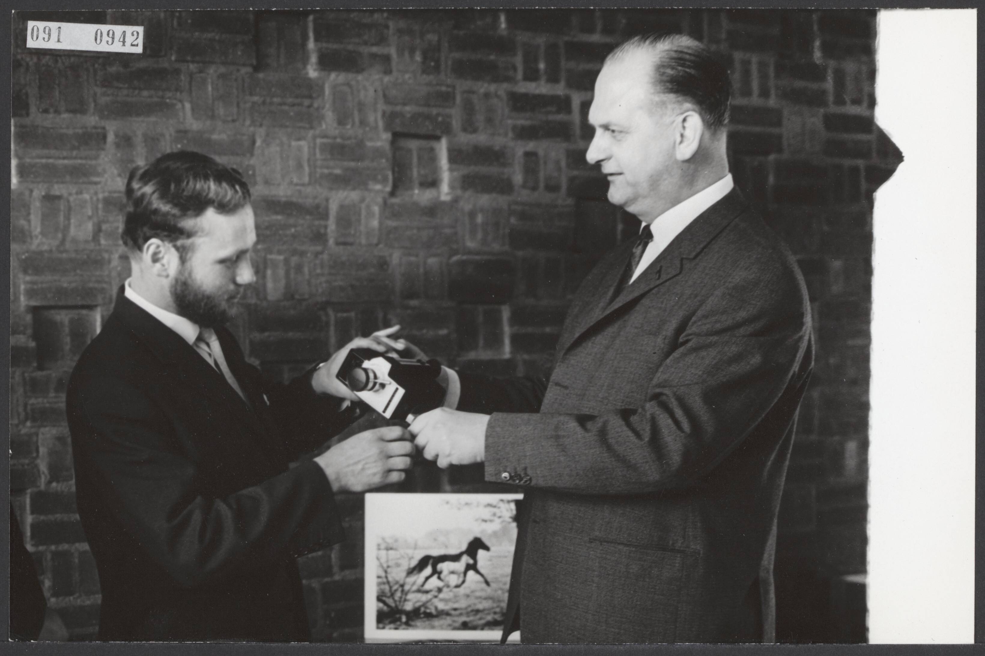Fotocollectie Elsevier Binnenland — Peter van Breukelen, voorzitter van de Stichting World Press Photo, heeft in het Haags Gemeentemuseum de Publieksprijs van de tentoonstelling 1963 uitgereikt. Deze was voor de jonge Duitse fotograaf, Peter Thomann (rechts), die een merrie met veulen fotografeerde — Foto: Koch, Eric / Anefo. Licentie: Set B: Rechtenvrij / Publiek Domein. Bron: Nationaal Archief. http://hdl.handle.net/10648/ae217a9e-d0b4-102d-bcf8-003048976d84