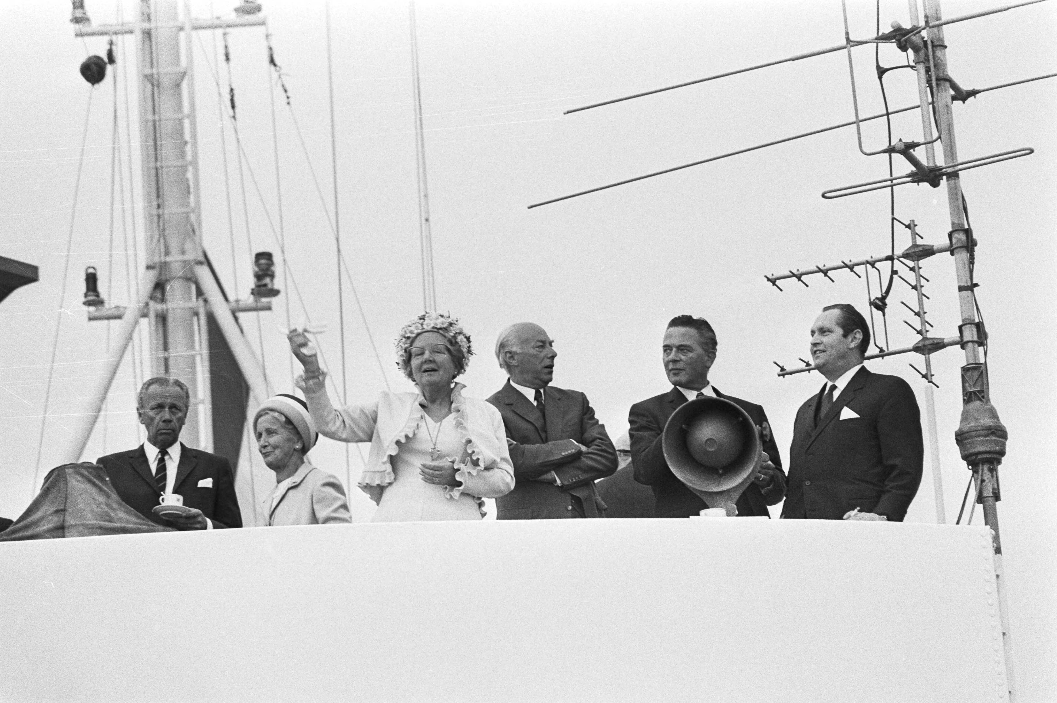 Hare Majesteit opent Havenmond, Scheveningen — Koningin Juliana zwaait vanaf een schip — Foto: Fotograaf Onbekend / Anefo. Licentie: Set B: Rechtenvrij / Publiek Domein. Bron: Nationaal Archief. http://hdl.handle.net/10648/abc04d84-d0b4-102d-bcf8-003048976d84