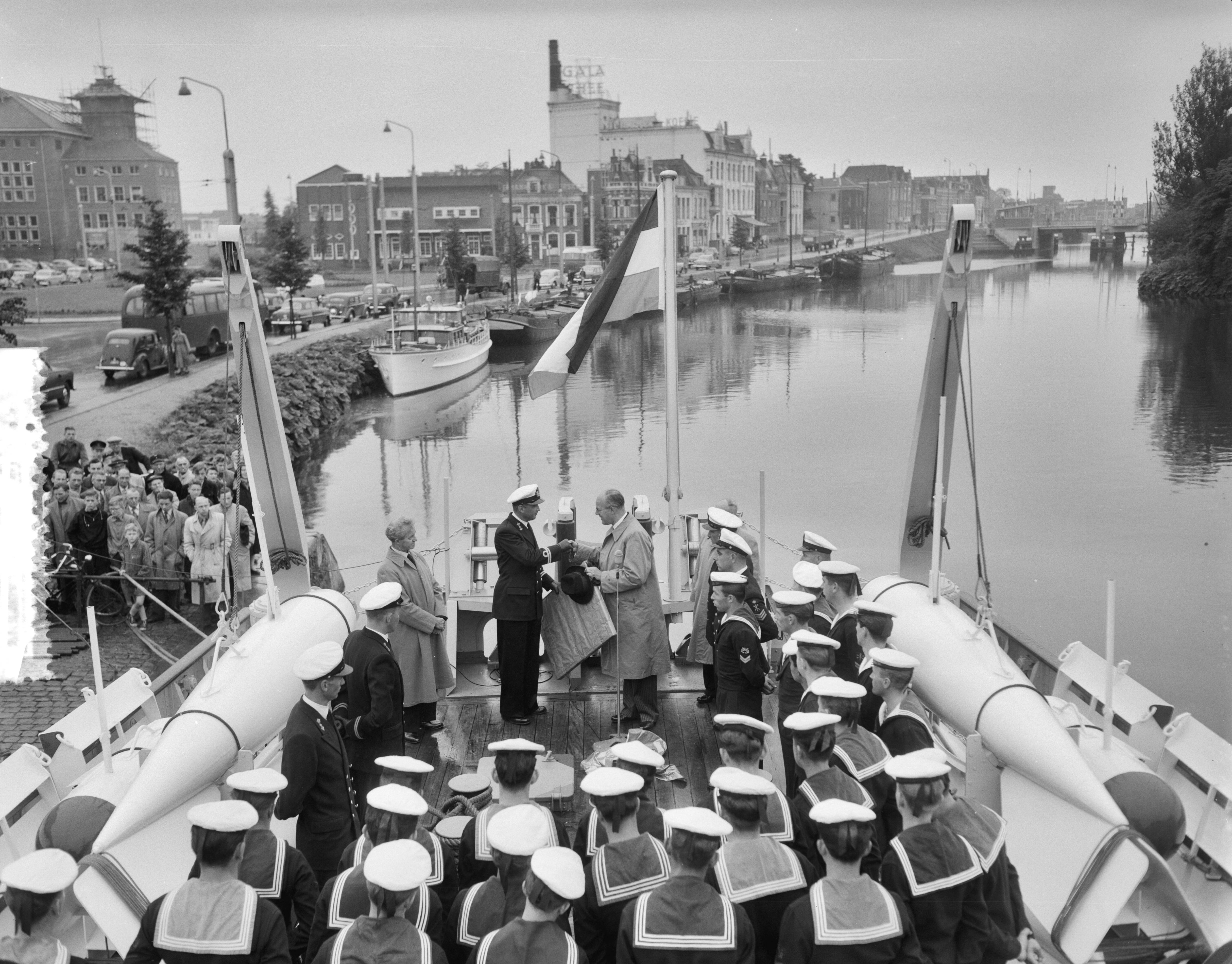 Overdracht en indienststelling van de kustmijnenveger Hr. Ms. "Lochem" in het Verbindingskanaal te Groningen — Overdracht en indienststelling van de kustmijnenveger Hr. Ms. "Lochem" in het Verbindingskanaal te Groningen. De burgemeester van Lochem, H.A. Beusekamp overhandigt een van de twee acquarellen aan de commandant, luitenant-ter-zee 2e klasse D. Lindner — Foto: Behrens, Herbert F. / Anefo. Licentie: Set B: Rechtenvrij / Publiek Domein. Bron: Nationaal Archief. http://hdl.handle.net/10648/a94bb9ee-d0b4-102d-bcf8-003048976d84
