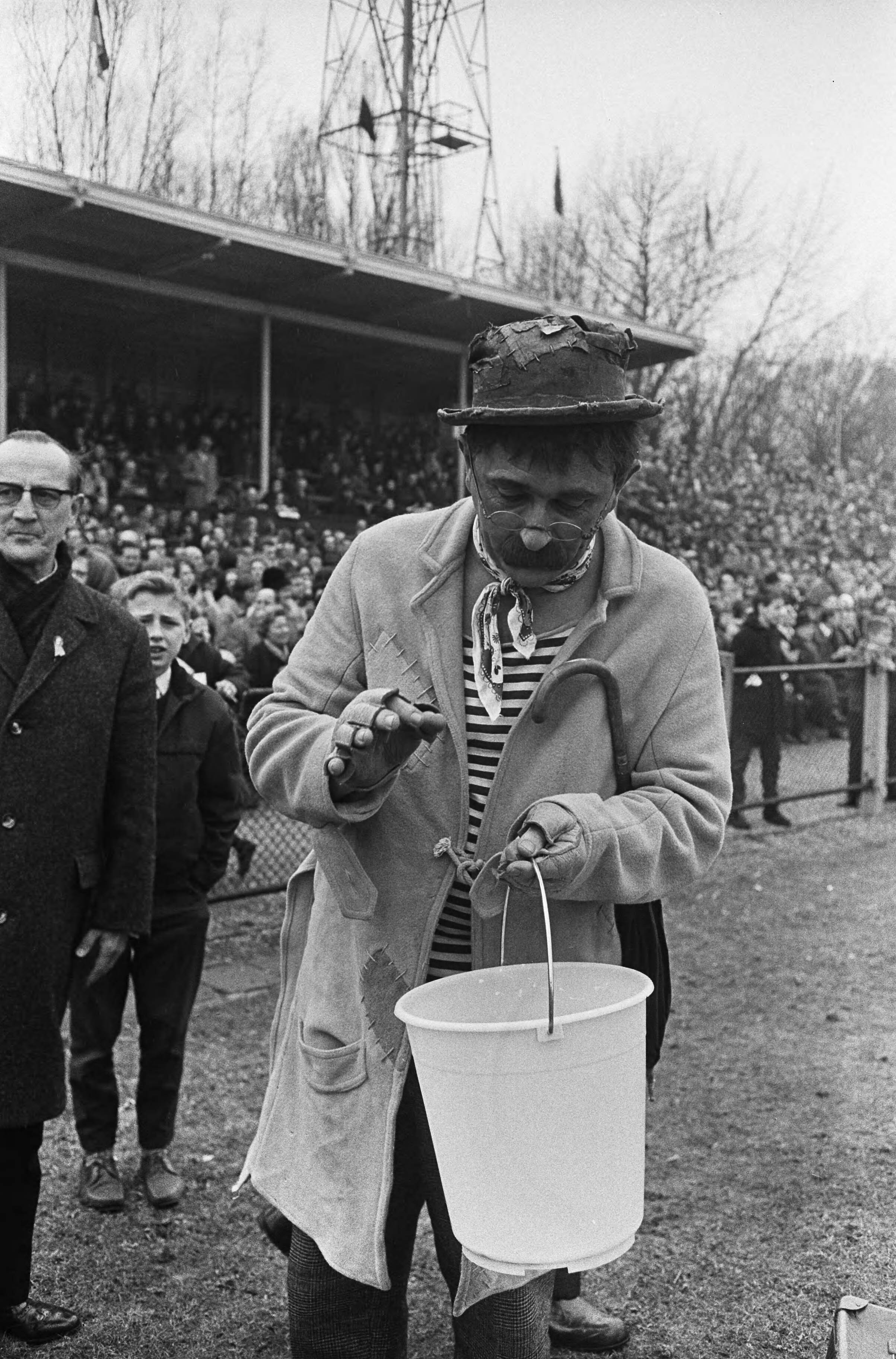 Fotocollectie Anefo — Artiestenvoetbal in Den Haag, Dorus (Tom Manders) telt de "buit" in zijn emmertje — Foto: Koch, Eric / Anefo. Licentie: Set B: Rechtenvrij / Publiek Domein. Bron: Nationaal Archief. http://hdl.handle.net/10648/aa9910ee-d0b4-102d-bcf8-003048976d84