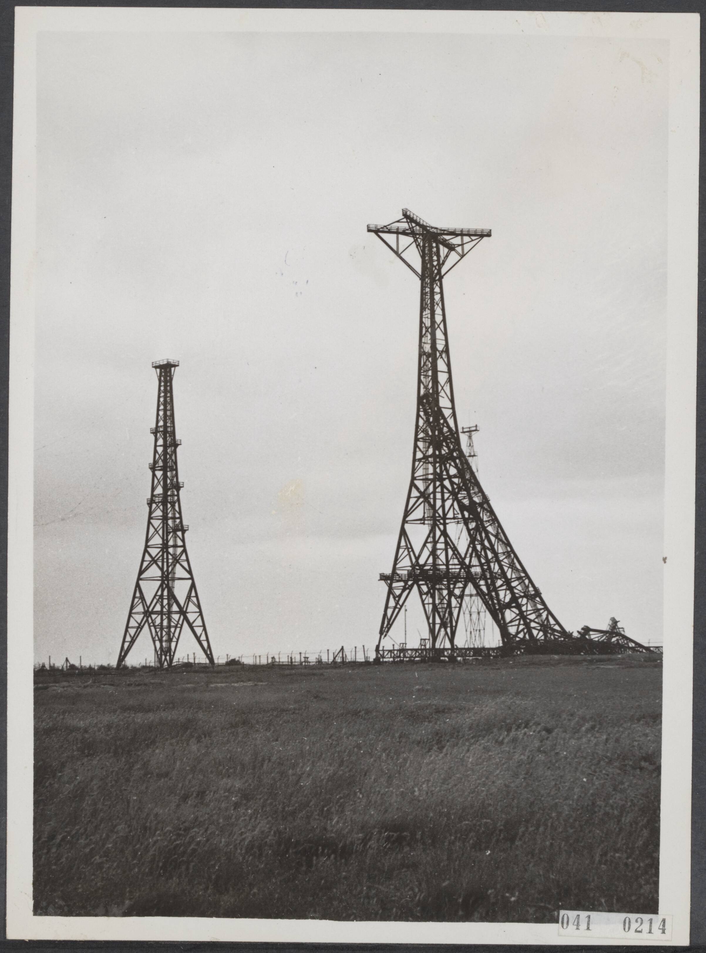 Fotocollectie Elsevier Binnenland — De zender van Huizen is nog buiten gebruik, omdat een van de masten in mei 1940 door de genie werd opgeblazen. Het gevaarte brak doormidden en viel tegen een van andere zendmasten — Foto: Internationale Clichéfabrieken Pax Holland N.V. Licentie: Set B: Rechtenvrij / Publiek Domein. Bron: Nationaal Archief. http://hdl.handle.net/10648/adf6225e-d0b4-102d-bcf8-003048976d84