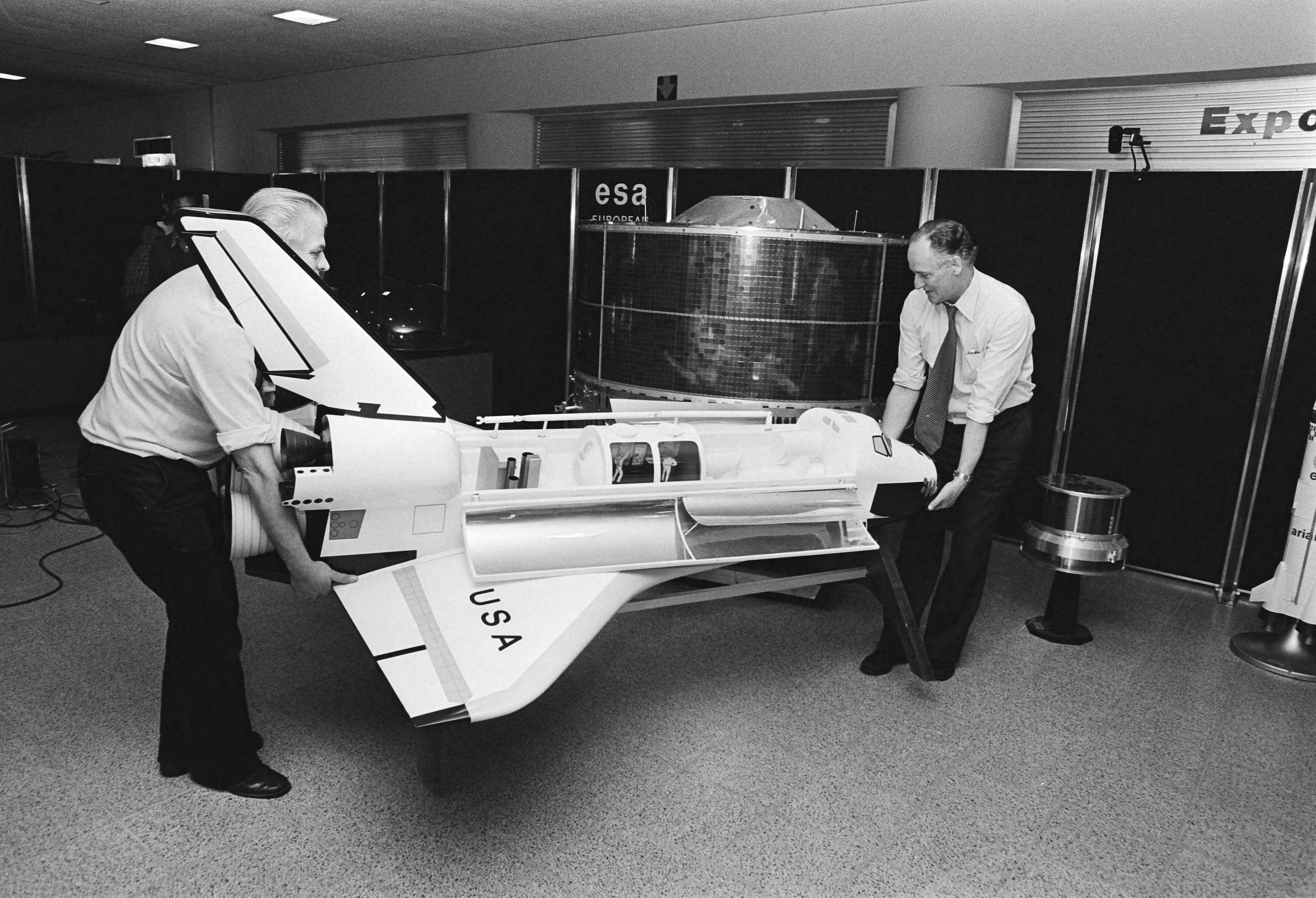 Fotocollectie Anefo — Morgen Sterrekunde-dag in Congrescentrum in Den Haag, georganiseerd door Teleac, 2 medewerkers van ESA plaatsen model van Amerikaanse Space-shuttle — Foto: Antonisse, Marcel / Anefo. Licentie: Set B: Rechtenvrij / Publiek Domein. Bron: Nationaal Archief. http://hdl.handle.net/10648/acf6f202-d0b4-102d-bcf8-003048976d84