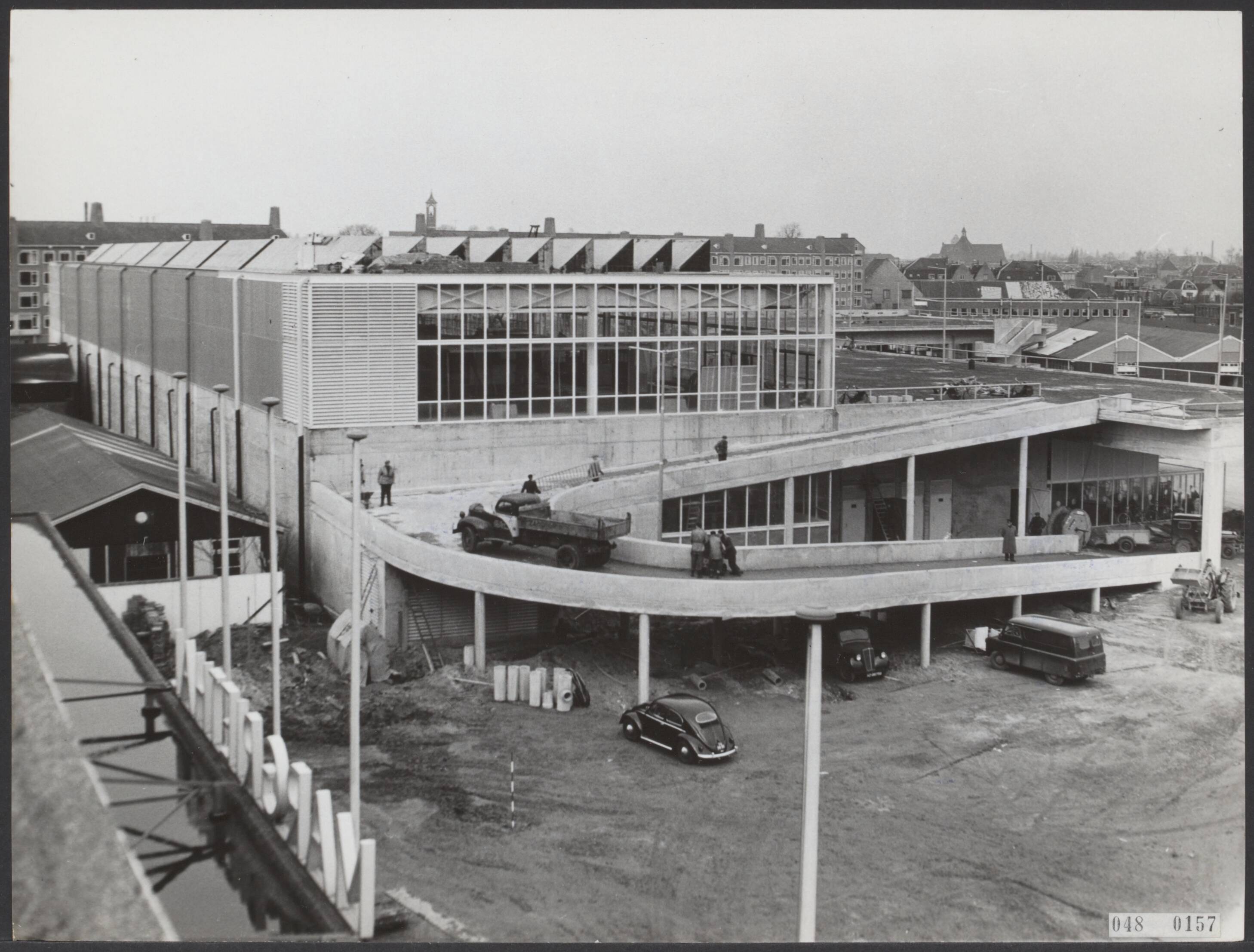 Fotocollectie Elsevier Binnenland — De nieuwe hal op het Jaarbeursterrein te Utrecht, de Koningin Julianahal, is zo goed als gereed. De hal aan de Croeselaan te Utrecht zal op 12 maart 1956 t.g.v. het 40-jarig bestaan van de Kon. Ned. Jaarbeurs door de koningin verricht worden. De nieuwe hal met de oprit voor auto's naar het platform voor de aanvoer van goederen naar de hoger verdieping. Op de voorgrond links een stukje, met de letters, van de Margriethal — Foto: Fotograaf Onbekend / Anefo. Licentie: Set B: Rechtenvrij / Publiek Domein. Bron: Nationaal Archief. http://hdl.handle.net/10648/ae00eeb4-d0b4-102d-bcf8-003048976d84