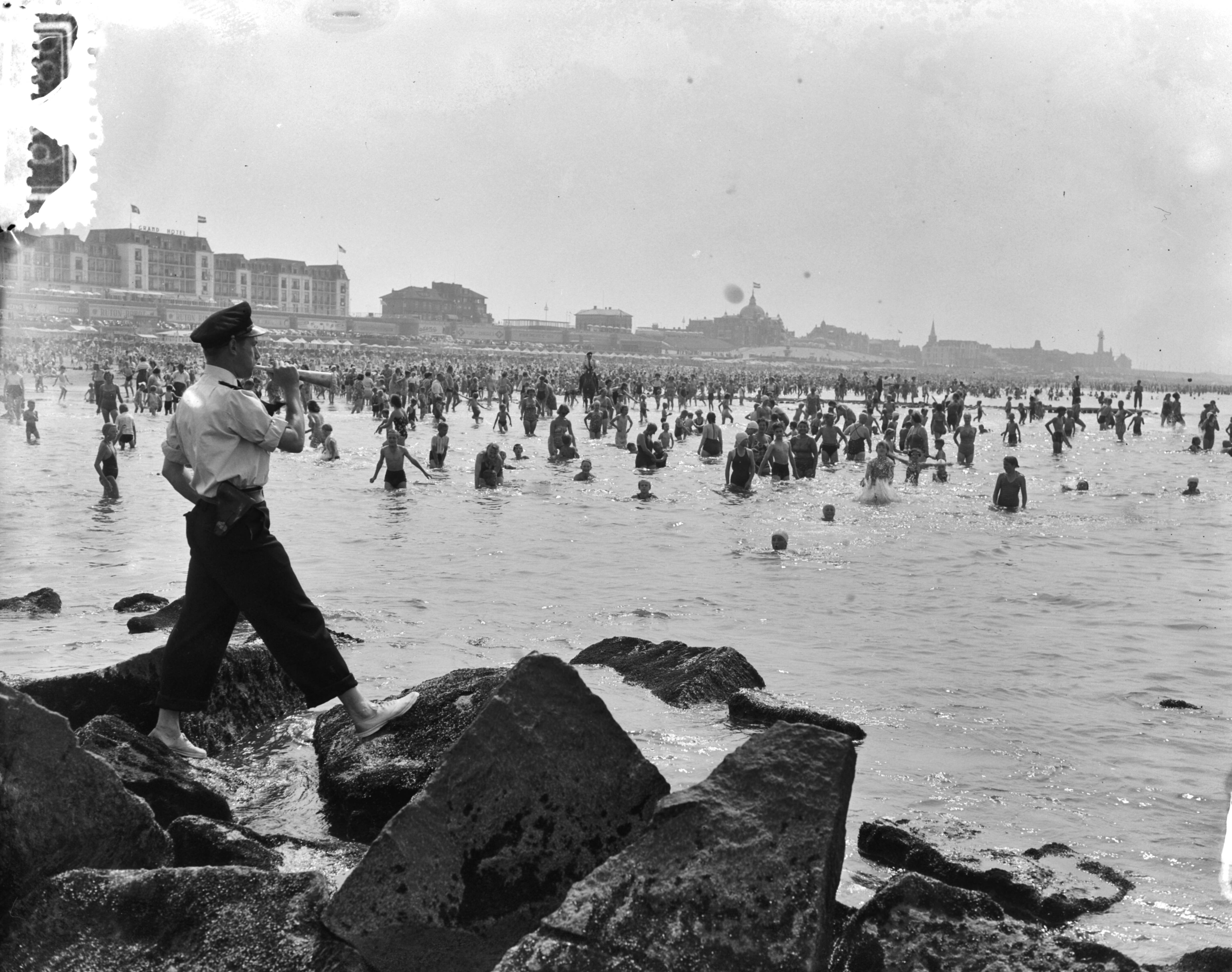 Fotocollectie Anefo — Hete dag aan het strand van Scheveningen. Politie waakt — Foto: Duinen, G.W. van / Anefo. Licentie: Set B: Rechtenvrij / Publiek Domein. Bron: Nationaal Archief. http://hdl.handle.net/10648/a910e85a-d0b4-102d-bcf8-003048976d84
