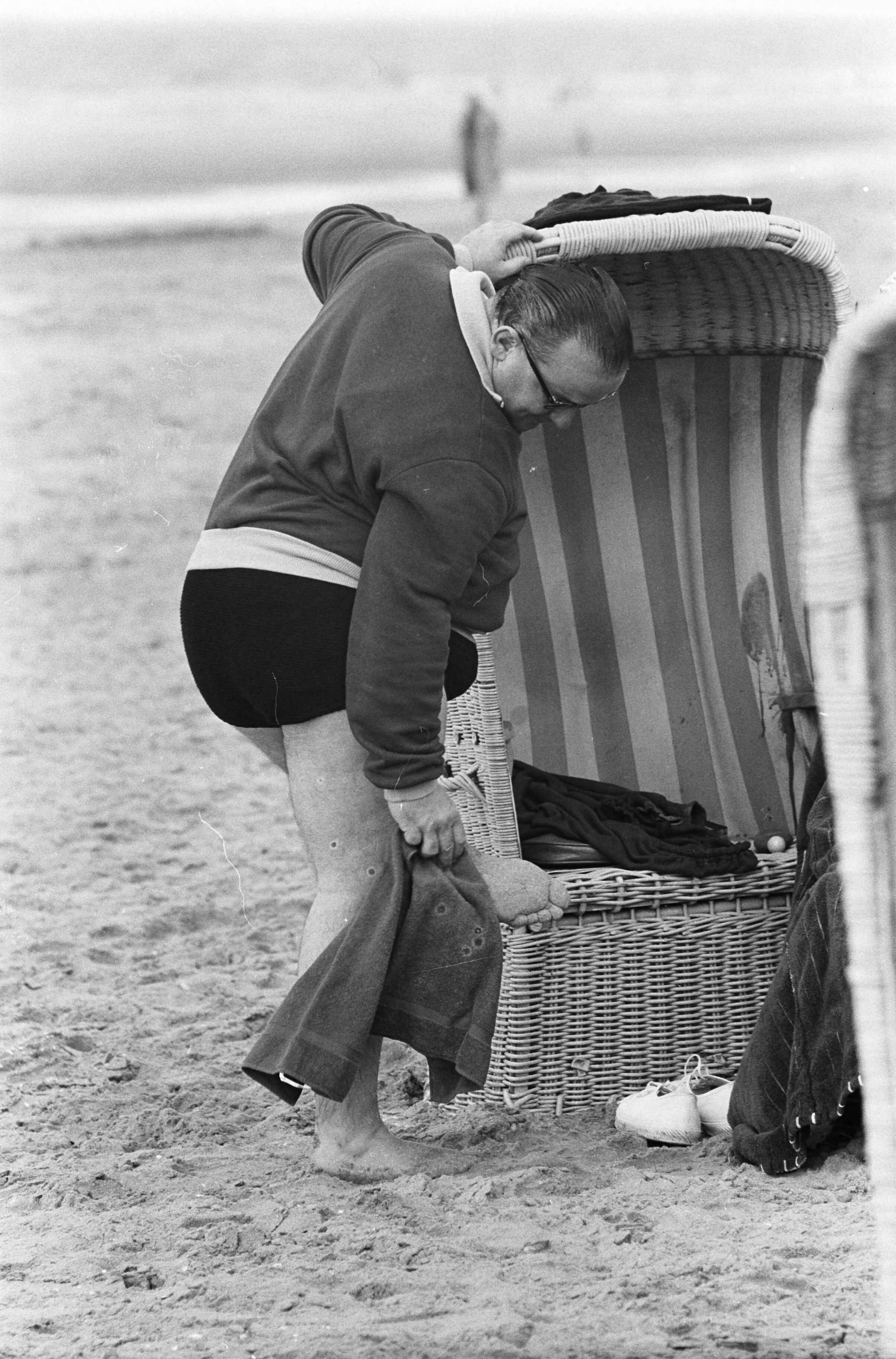 Fotocollectie Anefo — Strand Zandvoort. Corpulente heer probeert zich in broek te wurmen — Foto: Pot, Harry / Anefo. Licentie: Set B: Rechtenvrij / Publiek Domein. Bron: Nationaal Archief. http://hdl.handle.net/10648/aa0b6c6c-d0b4-102d-bcf8-003048976d84