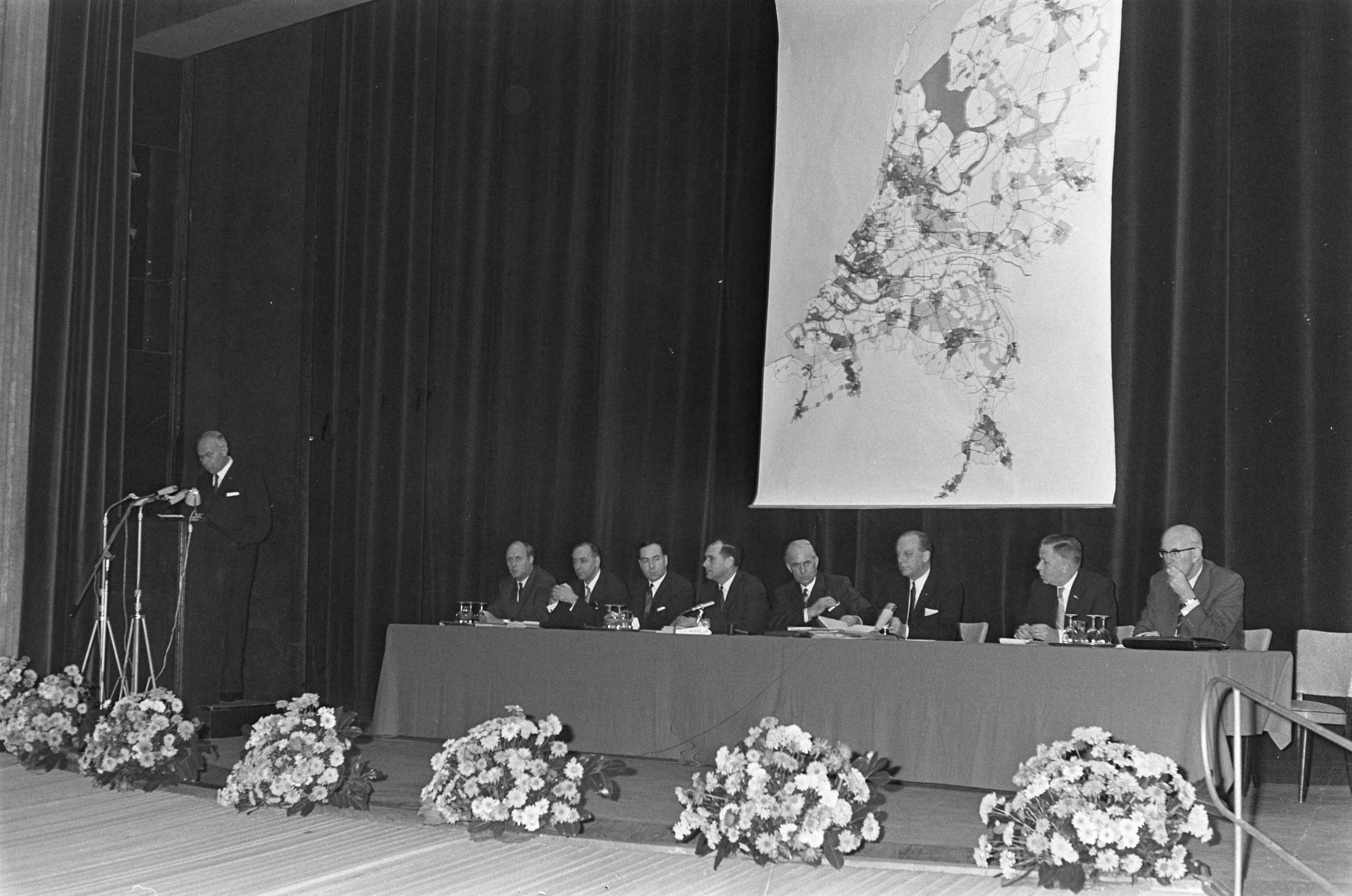 Fotocollectie Anefo — Nederlands Wegencongres te Utrecht, de bestuurstafel op achtergrond kaart wegennet — Foto: Merk, Ben / Anefo. Licentie: Set B: Rechtenvrij / Publiek Domein. Bron: Nationaal Archief. http://hdl.handle.net/10648/ab078ccc-d0b4-102d-bcf8-003048976d84