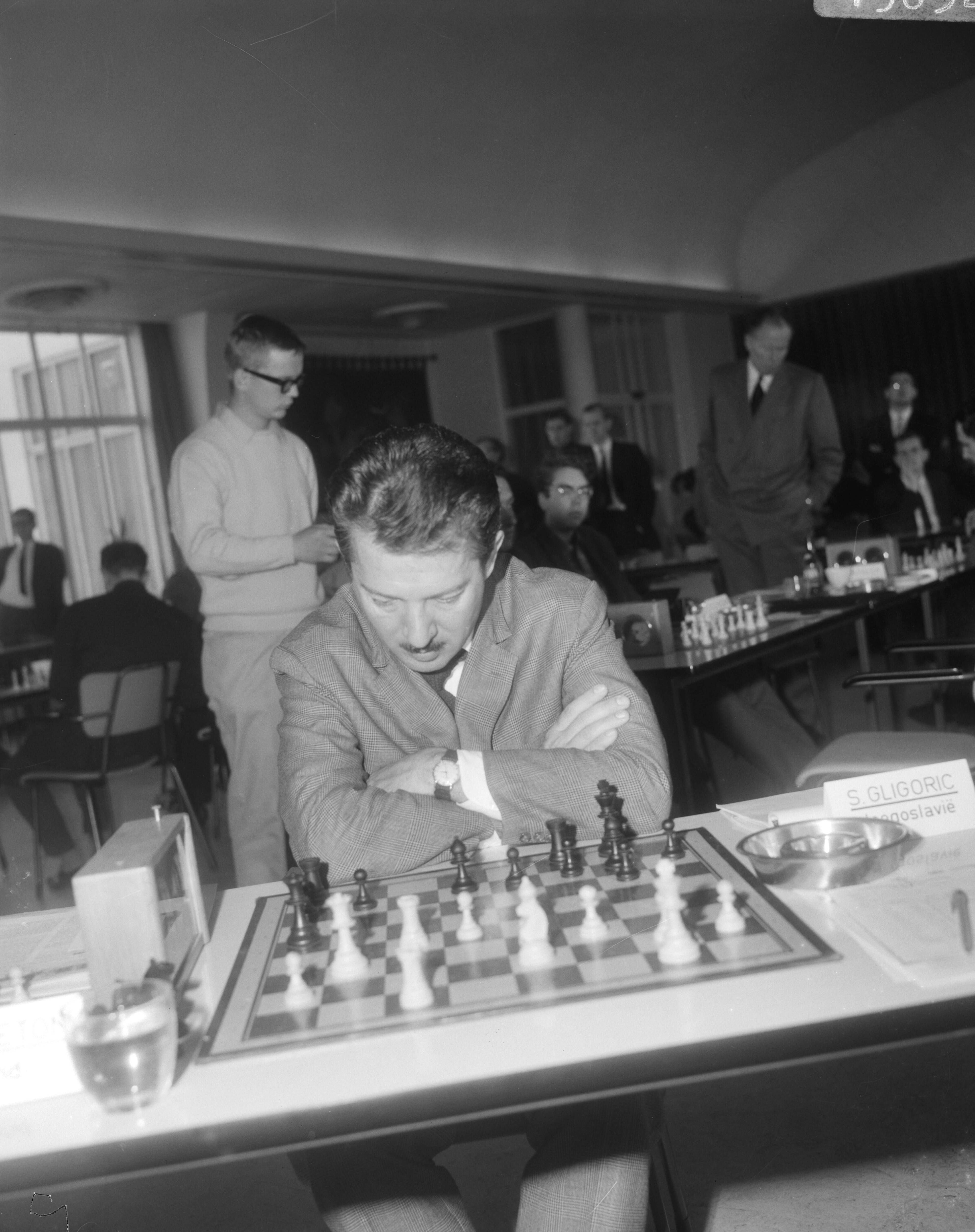 Fédération Internationale des Échecs (FIDE) -Zone schaaktoernooi 1966 in de kantine van 'De Nederlanden van 1845' te Den Haag — De Servische grootmeester Svetozar Gligoriæ aan het schaakbord — Foto: Bilsen, Joop van / Anefo. Licentie: Set B: Rechtenvrij / Publiek Domein. Bron: Nationaal Archief. http://hdl.handle.net/10648/ab001104-d0b4-102d-bcf8-003048976d84