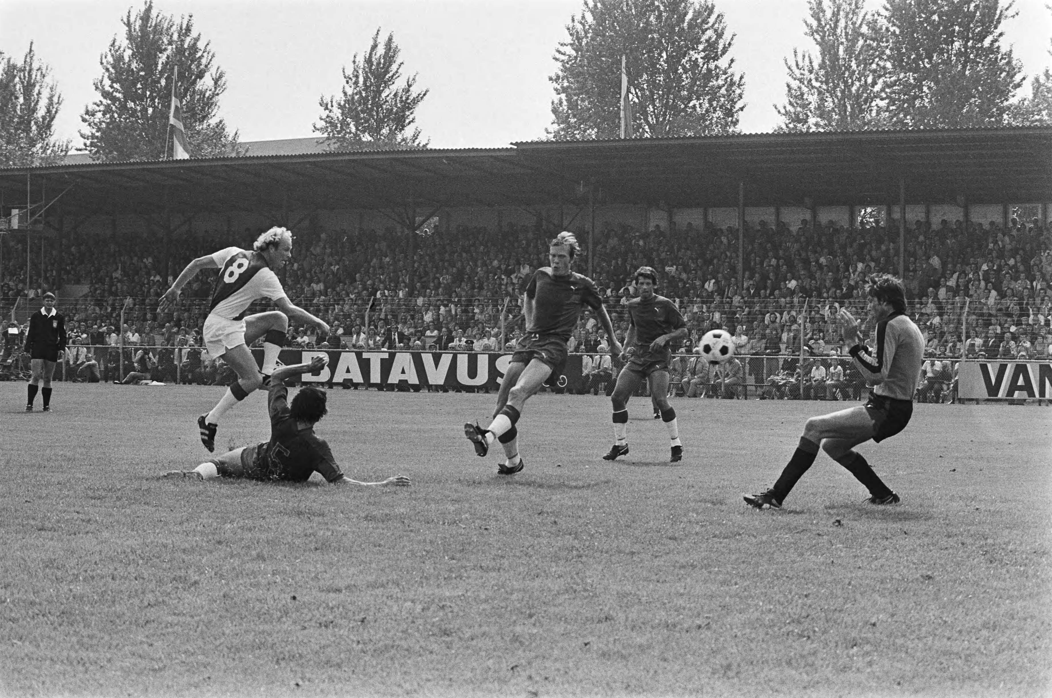 Fotocollectie Anefo — Haarlem tegen Ajax 0-2, Geels schiet de bal langs Boersma en opent daarmee de score, De Vries ligt op de grond, Haarlem-speler Huyg en Van de Berg — Foto: Verhoeff, Bert / Anefo. Licentie: Set B: Rechtenvrij / Publiek Domein. Bron: Nationaal Archief. http://hdl.handle.net/10648/aca11d96-d0b4-102d-bcf8-003048976d84