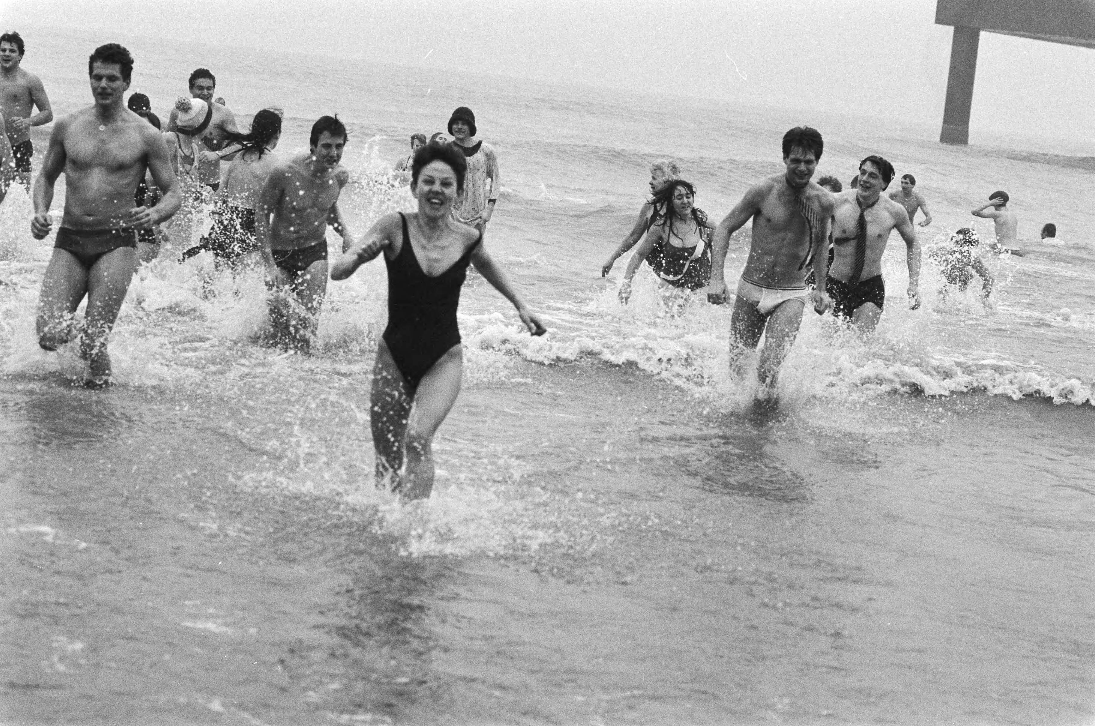 Traditionele Nieuwjaarsduik in Scheveningen — Mensen rennen terug uit het koude water — Foto: Bogaerts, Rob / Anefo. Licentie: Set B: Rechtenvrij / Publiek Domein. Bron: Nationaal Archief. http://hdl.handle.net/10648/ad4e3bb6-d0b4-102d-bcf8-003048976d84