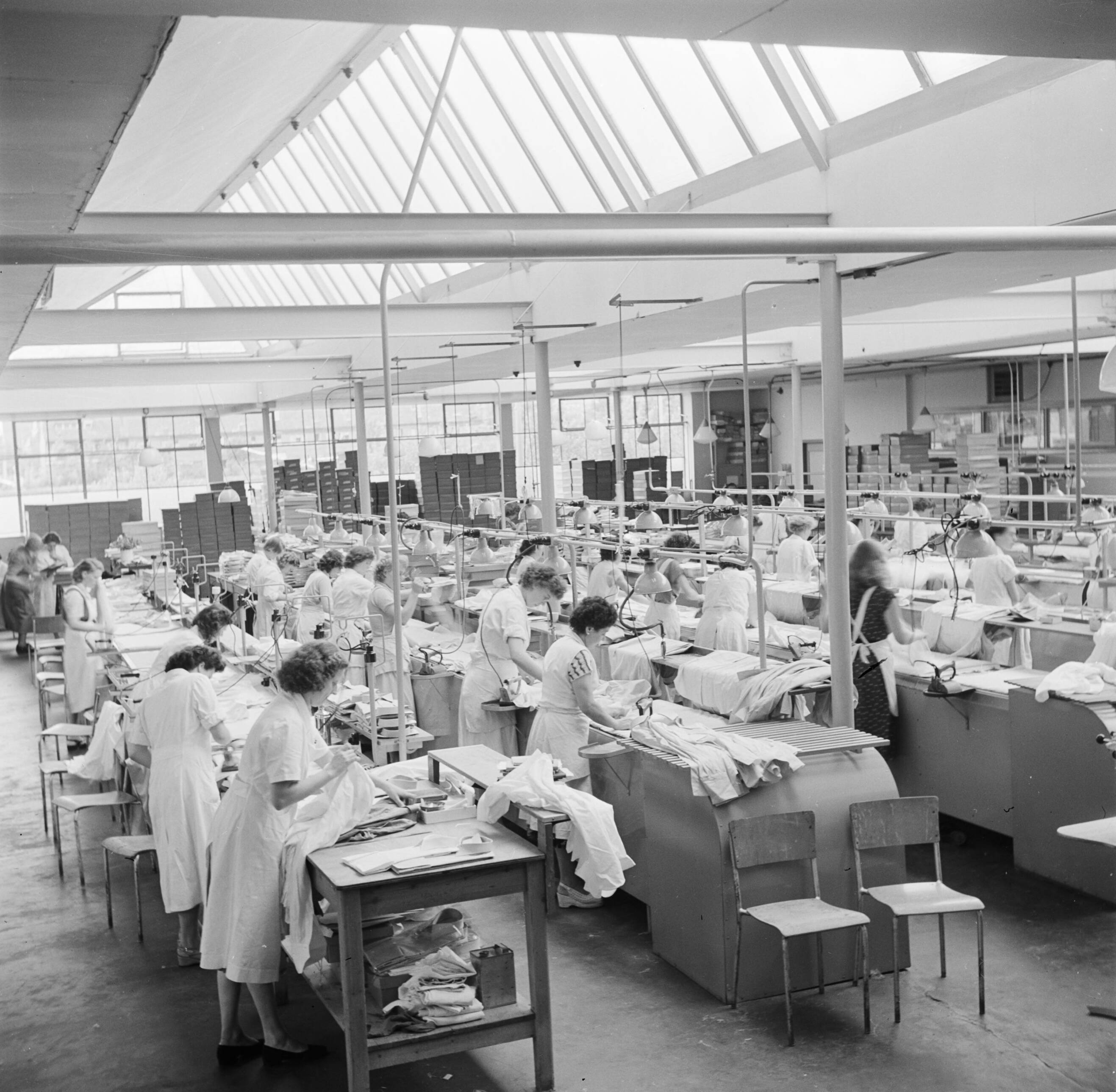 Reportage Kerko Haarlem — Zaal met strijksters aan strijkmachines bij overhemdenbedrijf Kerko — Foto: Poll, Willem van de. Licentie: Set B: Rechtenvrij / Publiek Domein. Bron: Nationaal Archief. http://hdl.handle.net/10648/aecbc76a-d0b4-102d-bcf8-003048976d84