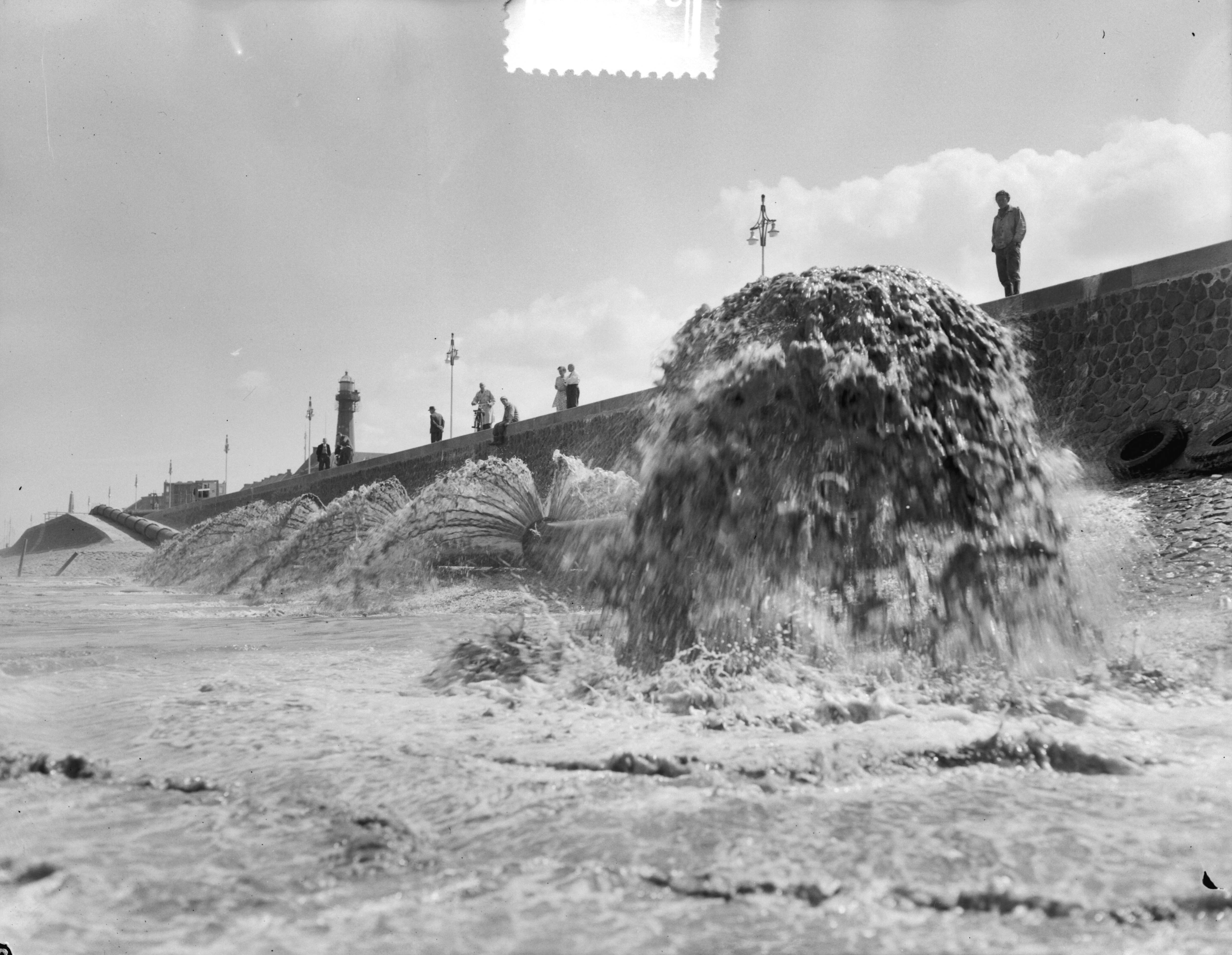 Fotocollectie Anefo — Spuitend zand vermengd met water op Scheveningse strand — Foto: Duinen, G.W. van / Anefo. Licentie: Set B: Rechtenvrij / Publiek Domein. Bron: Nationaal Archief. http://hdl.handle.net/10648/a90e1184-d0b4-102d-bcf8-003048976d84