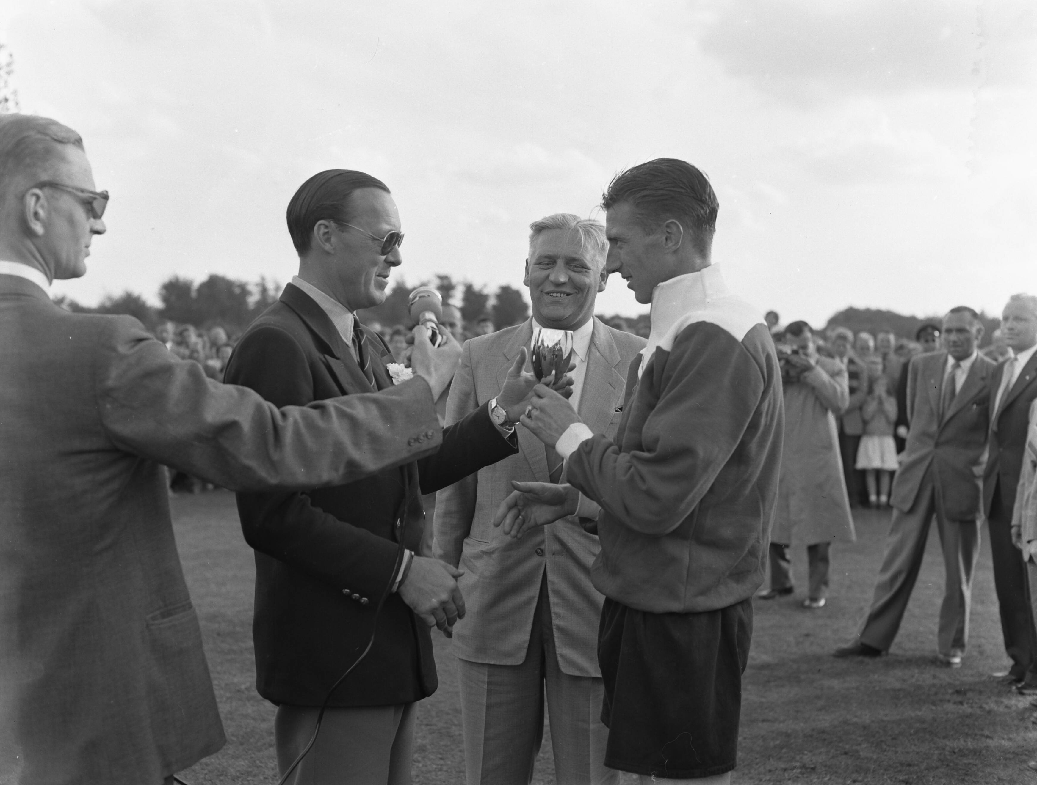 Fotocollectie Anefo — K.P.S. Sportdag te Baarn t.g.v. de verjaardag van Prins Bernhard. Erewedstrijd om de prins Bernhard-wisselbeker tussen Feijenoord en Amsterdam (2-1). Prins Bernhard reikt prijzen uit. De aanvoerder van Feijenoord ontvangt de wisselbeker — Foto: Pot, Harry / Anefo. Licentie: Set B: Rechtenvrij / Publiek Domein. Bron: Nationaal Archief. http://hdl.handle.net/10648/a937940a-d0b4-102d-bcf8-003048976d84