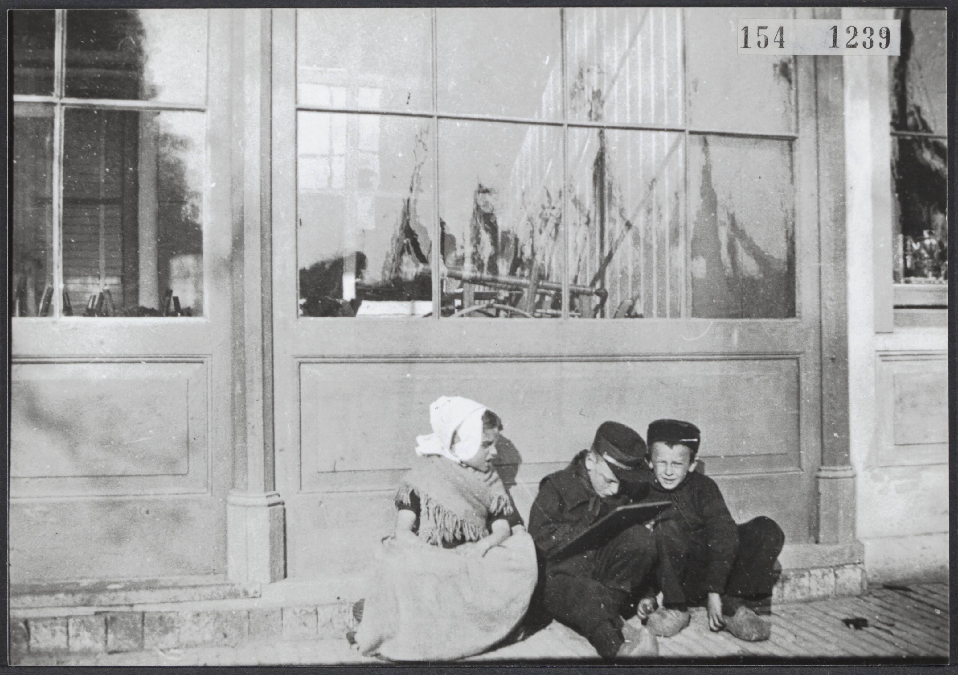 Serie Vanneufville (fotograaf uit Tourcoing 1855-1938) — Een kleine meisje en twee kleine jongens in klederdracht schrijven op een leitje. Vlissingen — Foto: Vanneufville, Leonce Bertile. Licentie: Set B: Rechtenvrij / Publiek Domein. Bron: Nationaal Archief. http://hdl.handle.net/10648/eea80d7b-55a6-3d9e-14f6-db97a9cbf45a