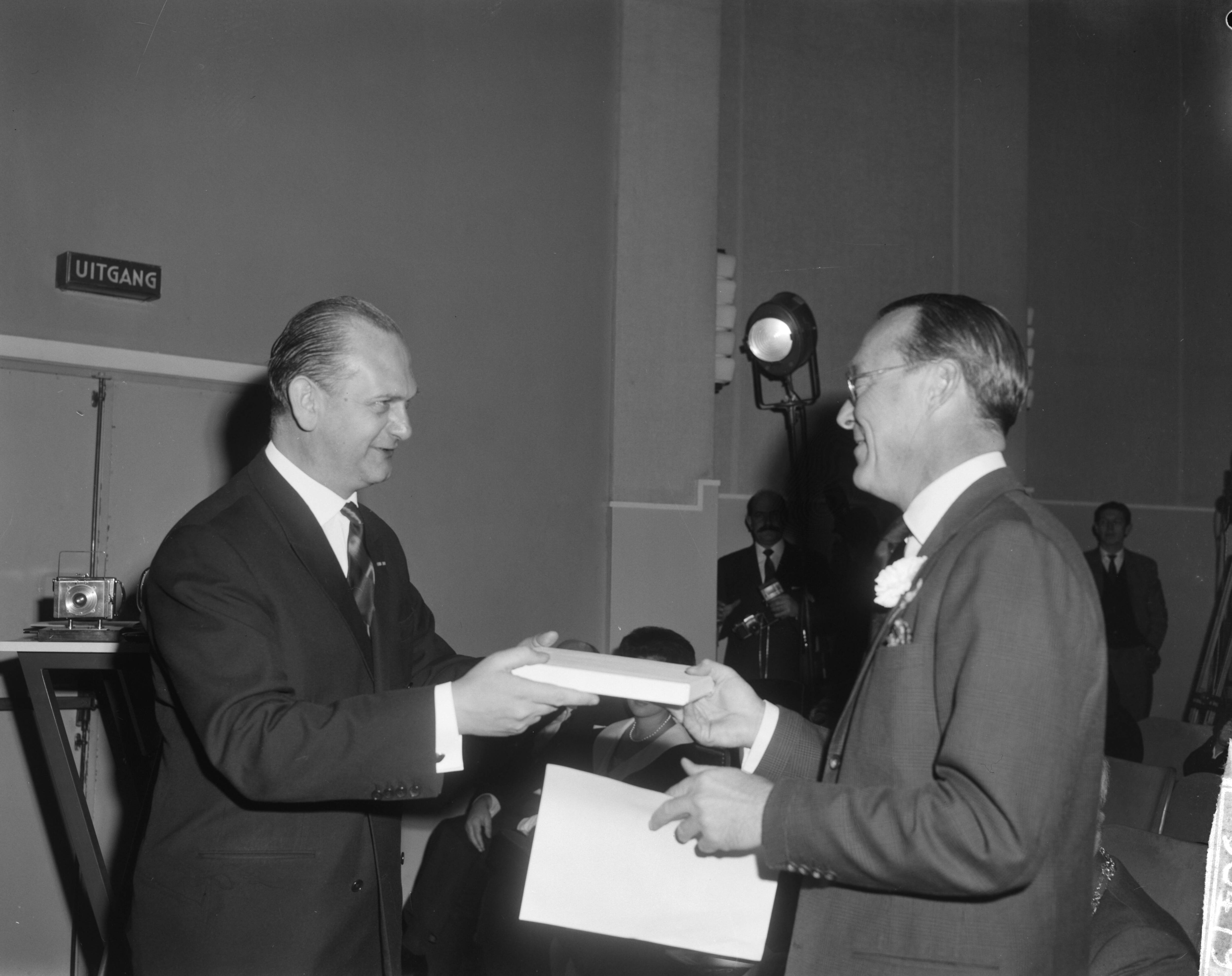 Fotocollectie Anefo — Prins Bernhard opende tentoonstelling World Press Photo 1963 in het Gemeentemuseum te Den Haag. De prins ontvangt een geschenk van ? — Foto: Bilsen, Joop van / Anefo. Licentie: Set B: Rechtenvrij / Publiek Domein. Bron: Nationaal Archief. http://hdl.handle.net/10648/aa5201ea-d0b4-102d-bcf8-003048976d84