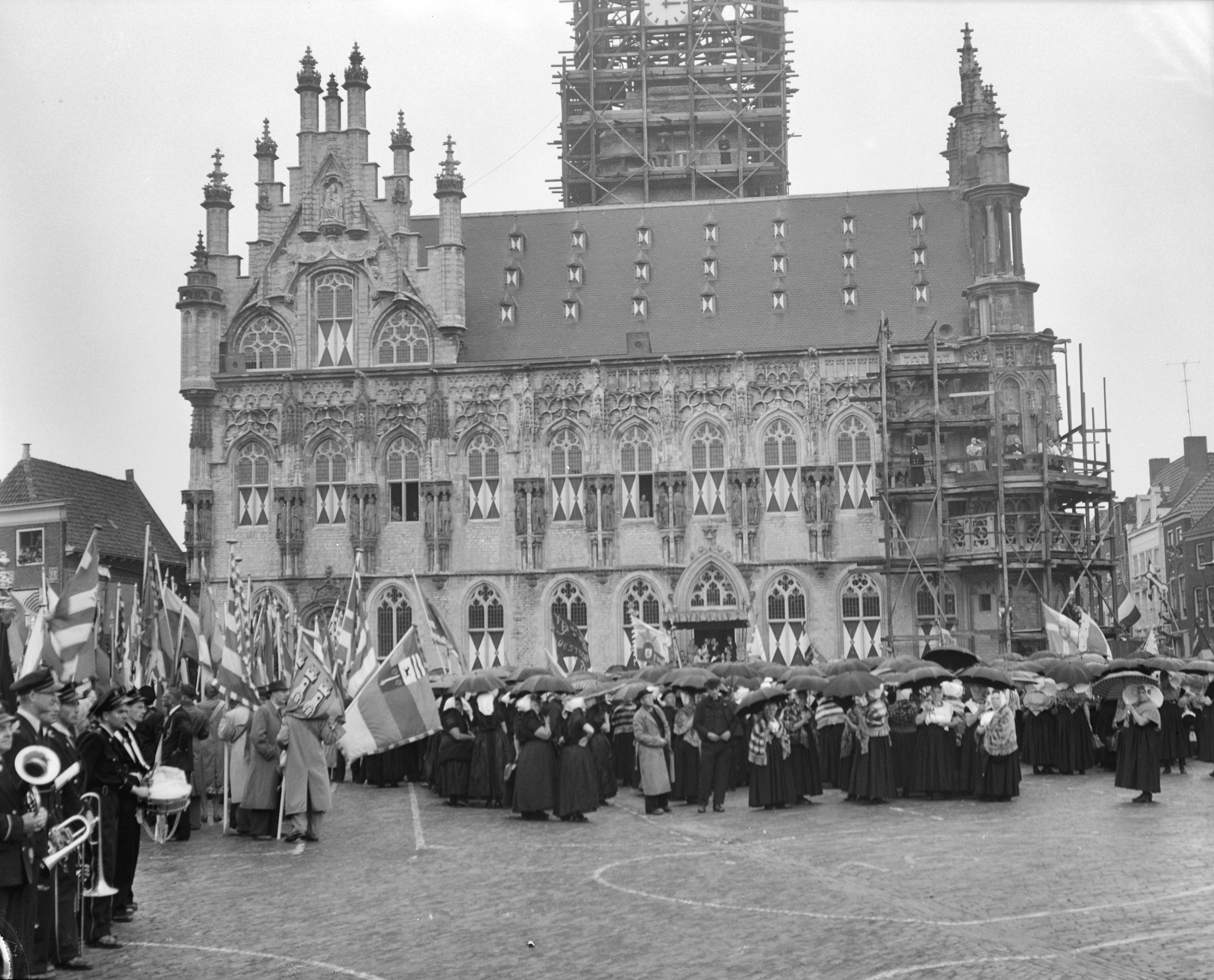 Koningin Juliana en prins Bernhard bezoeken Walcheren — Een menigte in klederdracht wacht voor het raadhuis van Middelburg op het koninklijk bezoek — Foto: Bilsen, Joop van / Anefo. Licentie: Set B: Rechtenvrij / Publiek Domein. Bron: Nationaal Archief. http://hdl.handle.net/10648/a9245944-d0b4-102d-bcf8-003048976d84