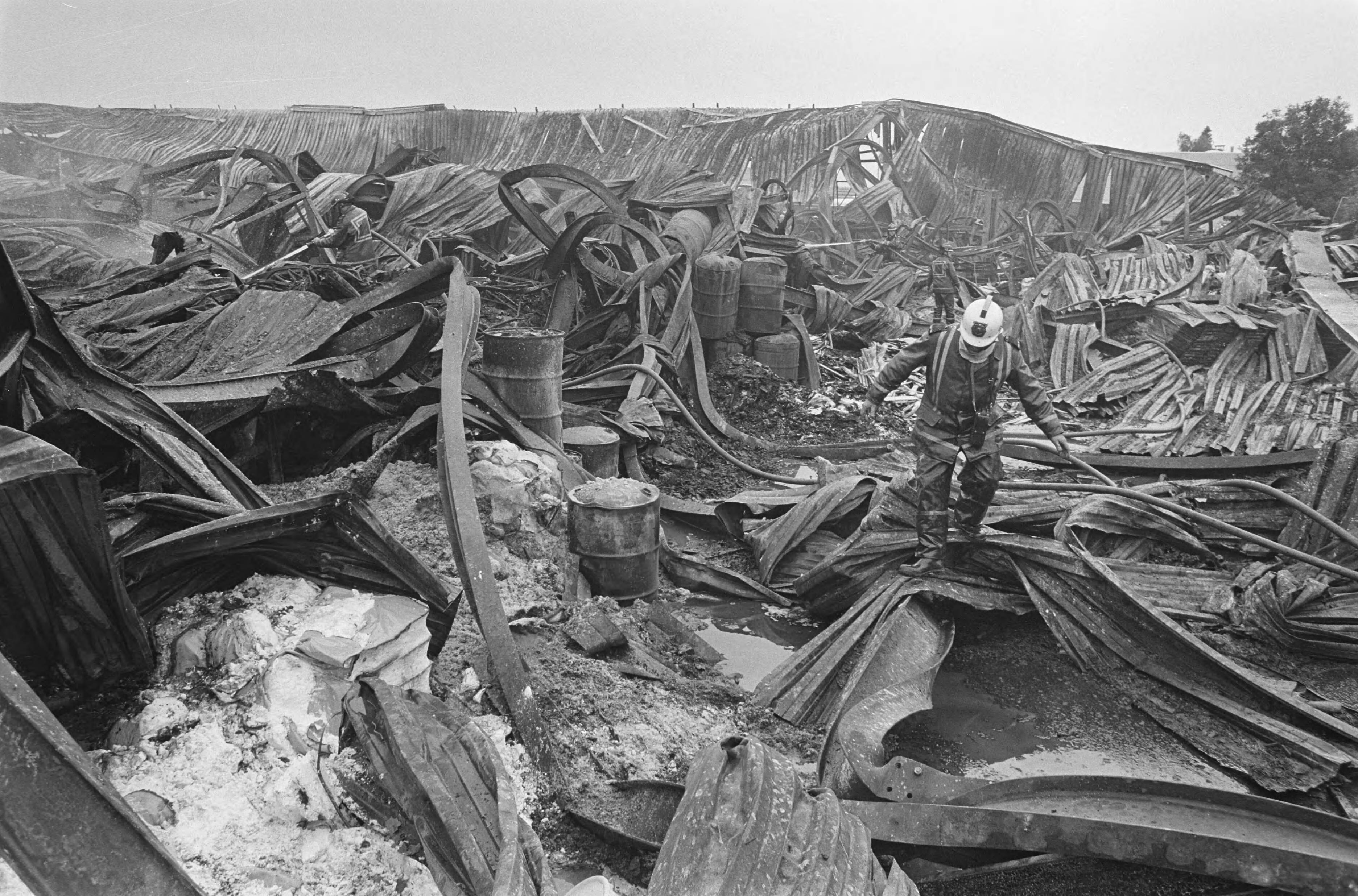 Fotocollectie Anefo — Verbrande vrachtwagens na brand in goederen-overslagbedrijf in Bodegraven; brandweerman temidden van ravage — Foto: Croes, Rob C. / Anefo. Licentie: Set B: Rechtenvrij / Publiek Domein. Bron: Nationaal Archief. http://hdl.handle.net/10648/ad56c916-d0b4-102d-bcf8-003048976d84