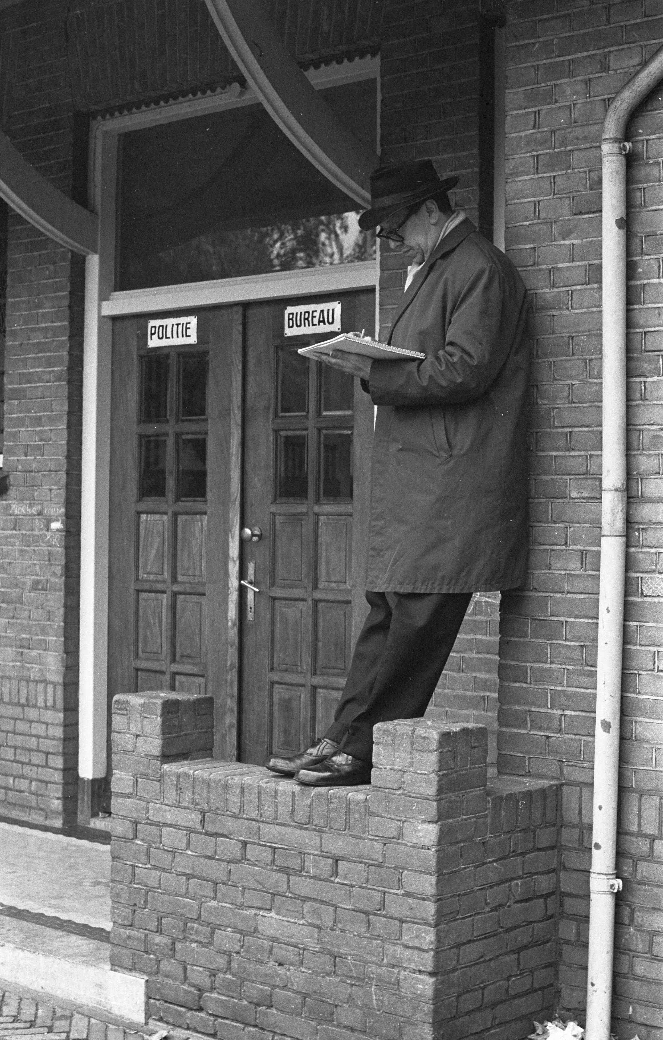 Fotocollectie Anefo — Drukte in Baarn in verband met ontsnapping moordenaar. Tekenaar Dekker bij het politiebureau — Foto: Rossem, Wim van / Anefo. Licentie: Set B: Rechtenvrij / Publiek Domein. Bron: Nationaal Archief. http://hdl.handle.net/10648/a9eb4c70-d0b4-102d-bcf8-003048976d84