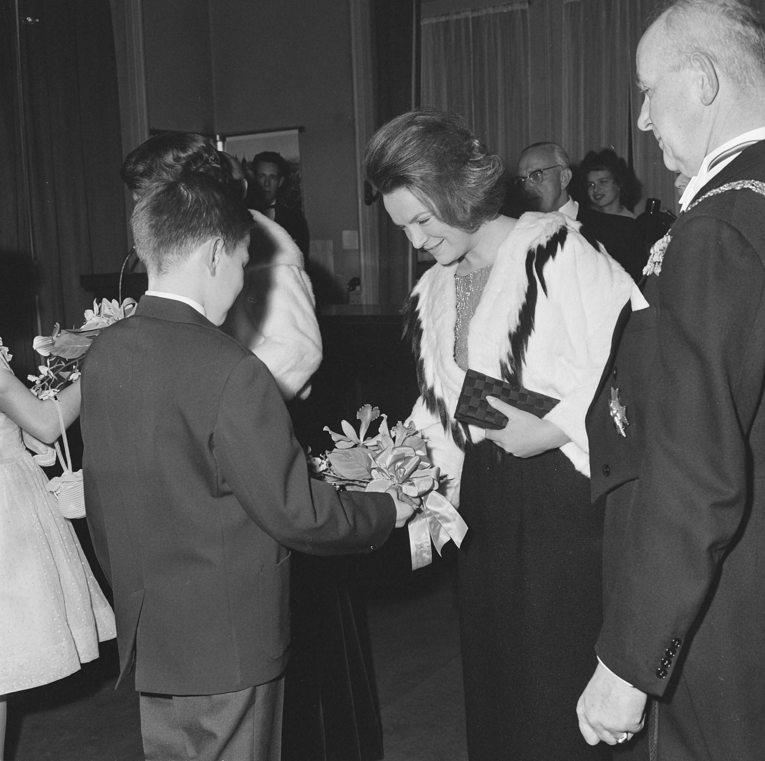 Fotocollectie Anefo — Prinses Beatrix en prinses Irene hebben in het Kurhaus te Scheveningen een galaconcert ter herdenking 150-jarig Koninkrijk bijgewoond. De prinsessen krijgen bloemen aangeboden door de kinderen van concertmeester Willem Noske. Rechts burgemeester Kolfschoten — Foto: Koch, Eric / Anefo. Licentie: Set B: Rechtenvrij / Publiek Domein. Bron: Nationaal Archief. http://hdl.handle.net/10648/aa52e8b2-d0b4-102d-bcf8-003048976d84
