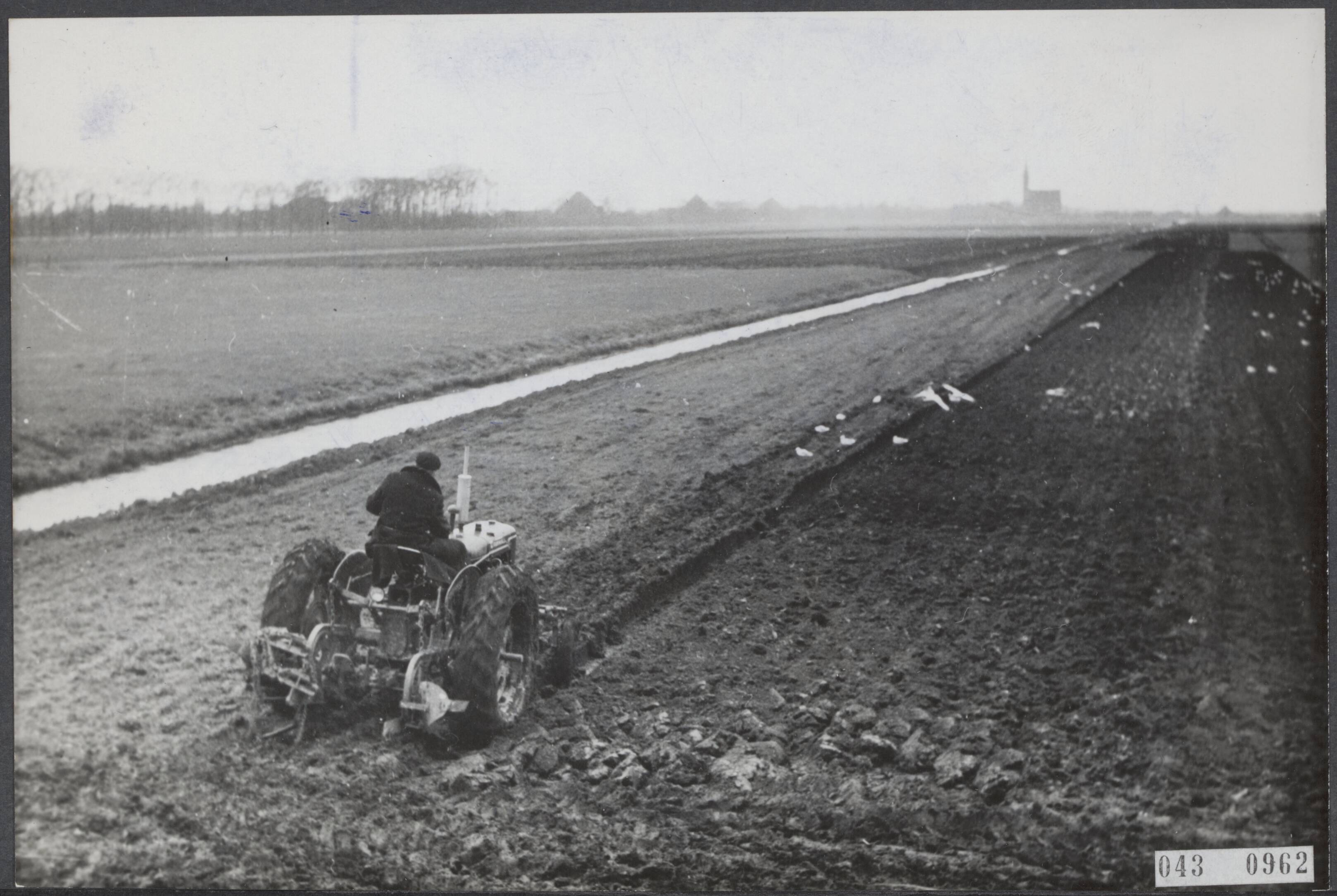 Fotocollectie Elsevier Binnenland — Groene weilanden worden zwarte cultuurgrond voor verbouwing van veevoeder: suikerbieten enz., hetgeen geschiedt op advies van het ministerie van Landbouw, opdat minder veevoeder in het buitenland behoeft te worden gekocht. Het scheuren van weiland in de Beemster, met op de achtergrond het juist gerestaureerde kerkje van Midden-Beemster — Foto: Fotograaf Onbekend / Anefo. Licentie: Set B: Rechtenvrij / Publiek Domein. Bron: Nationaal Archief. http://hdl.handle.net/10648/adf9bcde-d0b4-102d-bcf8-003048976d84